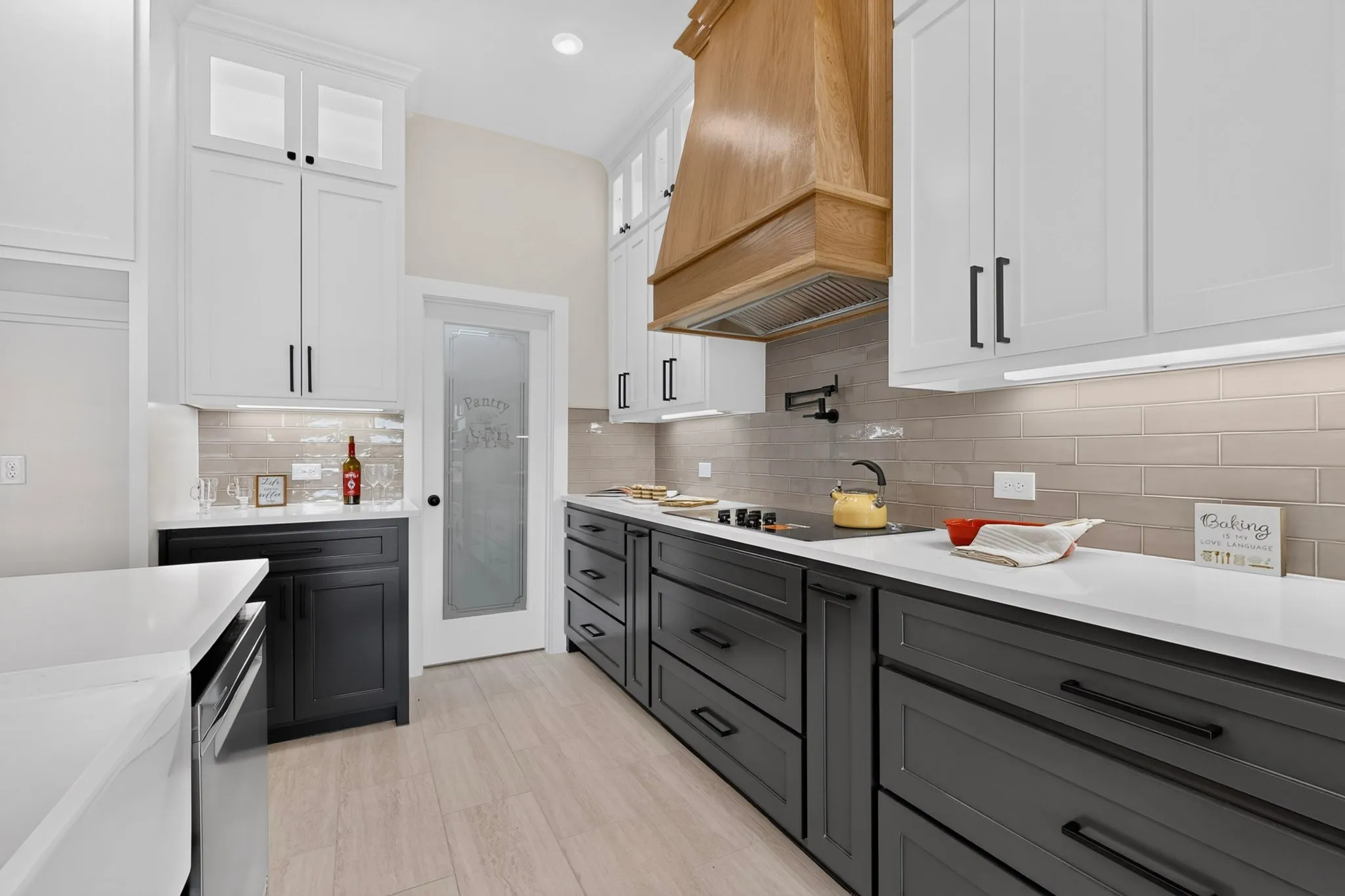 Kitchen featuring two-tone cabinetry, light wood-finish flooring, white countertop surfaces, a tiled backsplash, and an integrated cooktop