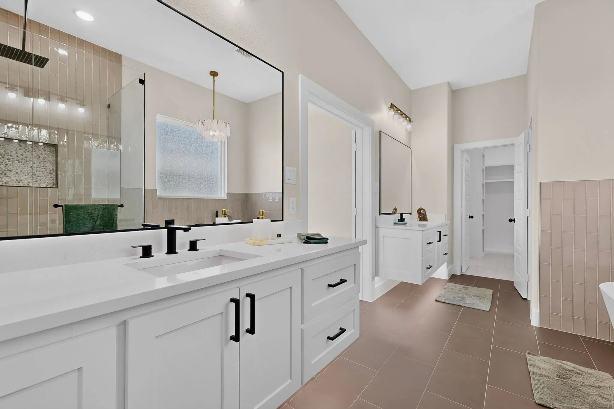 Primary Bathroom featuring dual vanities with white cabinetry, white quartz countertops, and matte black hardware