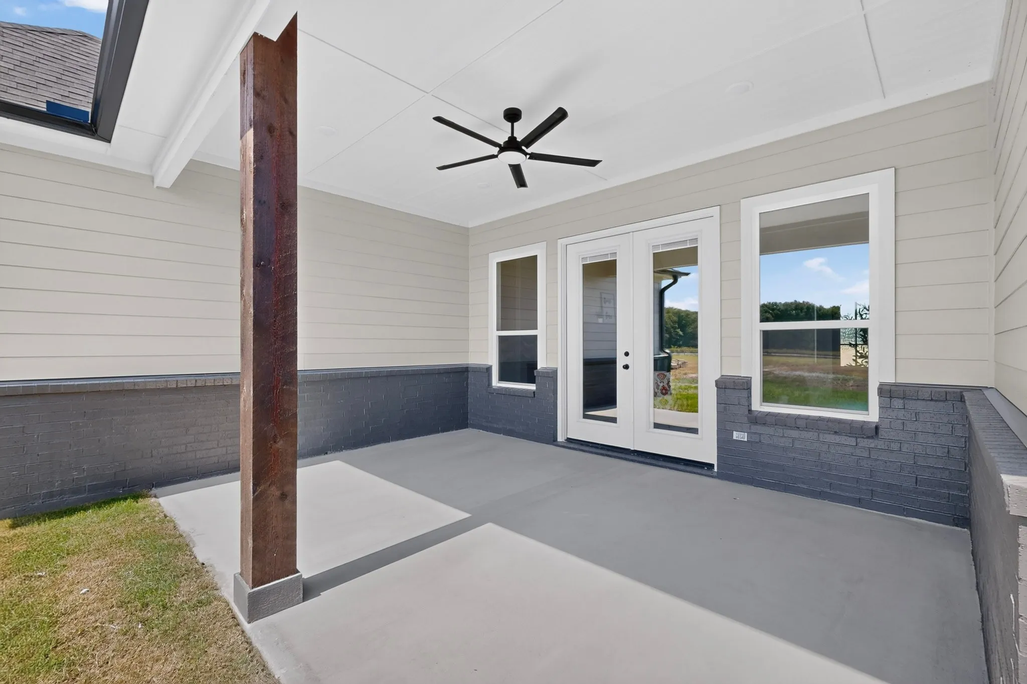 Covered patio featuring a ceiling fan, white French doors, and a wood-finish column