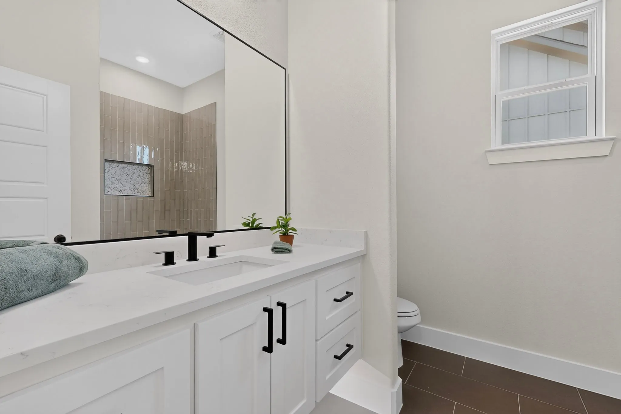 White vanity with black hardware, integrated sink, and white countertop