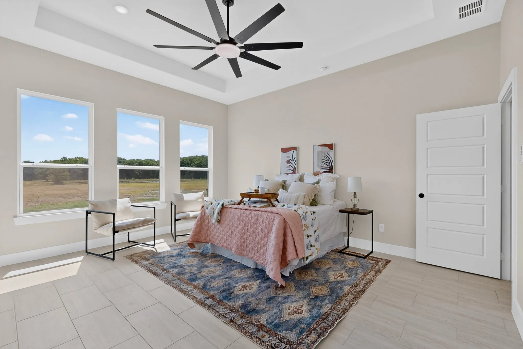 Tray ceiling with a modern ceiling fan, three large windows, tiled flooring, and a five-panel interior door