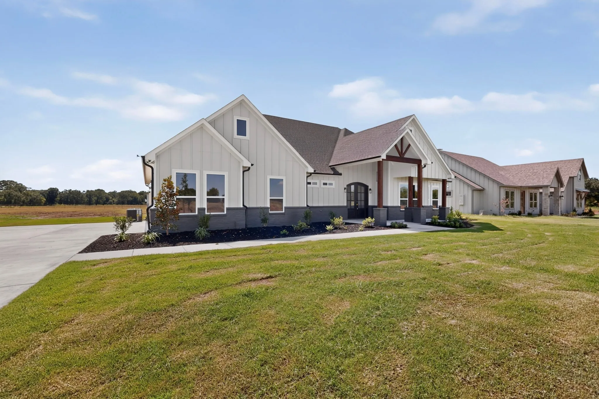 Single-story residence featuring board and batten siding, dark shingle roof, and a covered entry with exposed wood beams