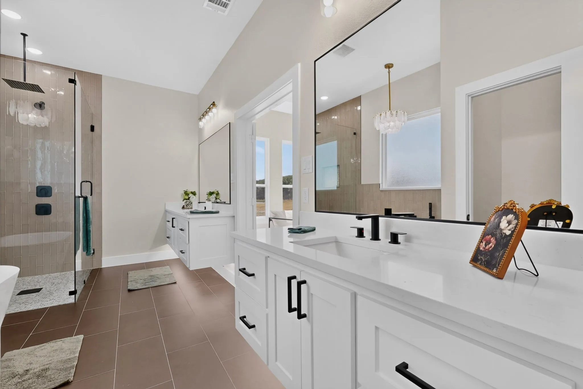 Dual vanities with white countertops, a frameless glass-enclosed shower, a built-in soaking tub, and matte black fixtures
