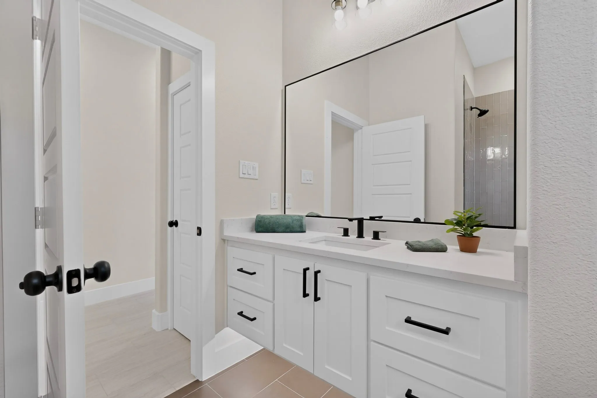 White shaker-style vanity with matte black hardware and a solid surface countertop