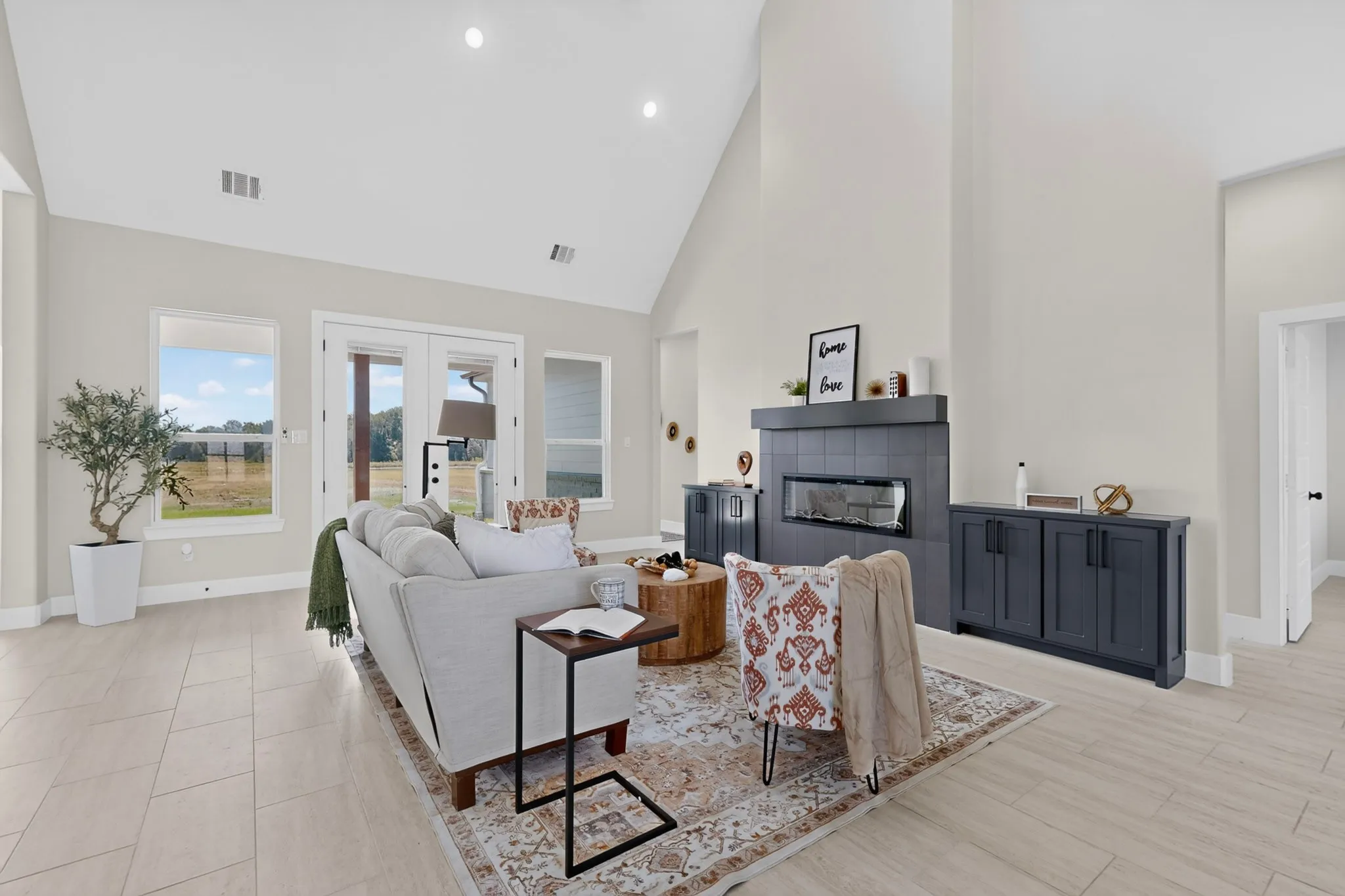 Vaulted ceiling with recessed lighting, tile flooring, modern fireplace with a linear firebox, and French doors