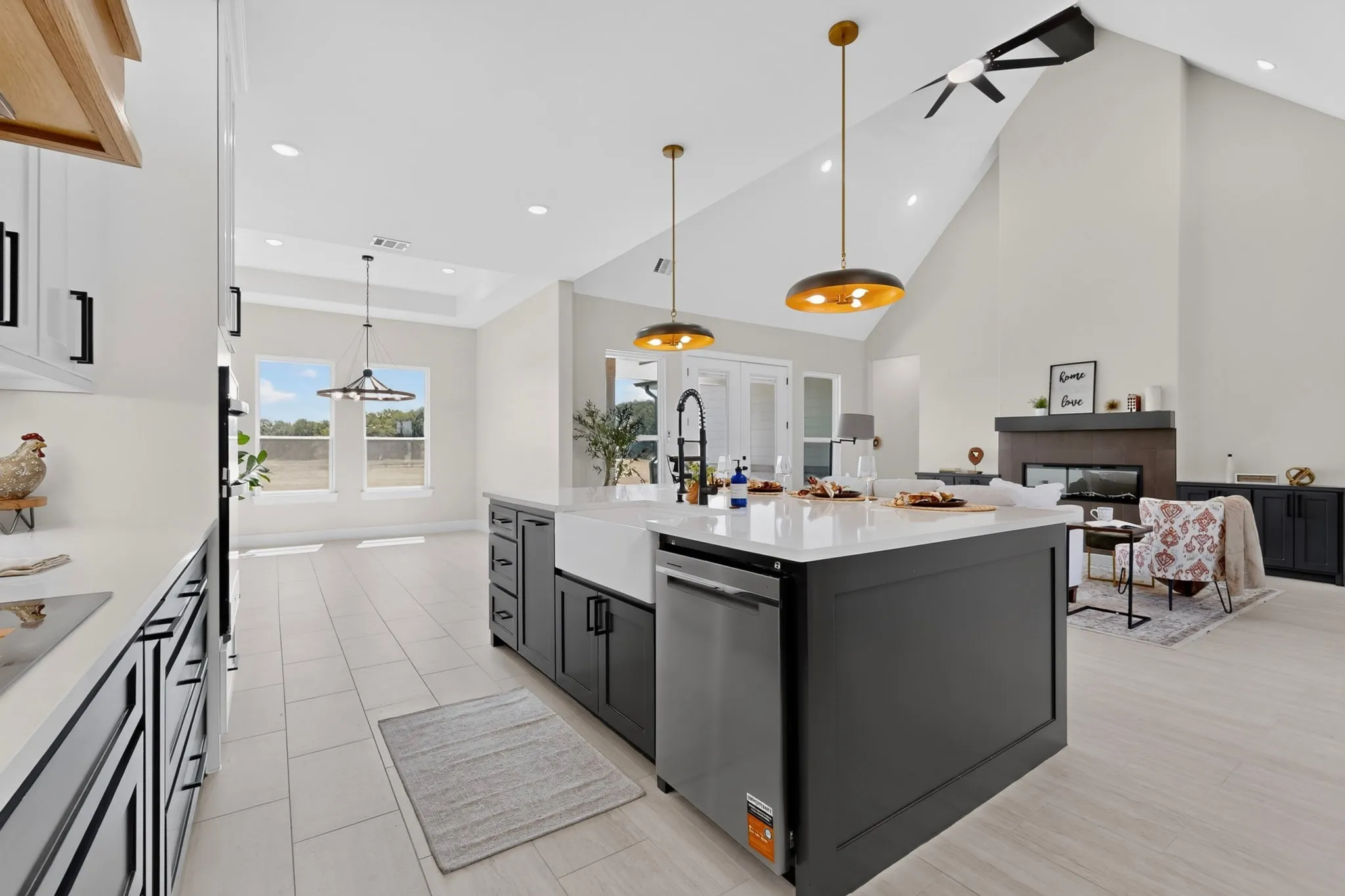 Spacious open-concept living area featuring a kitchen island with a farmhouse sink, stainless steel dishwasher, and pendant lighting