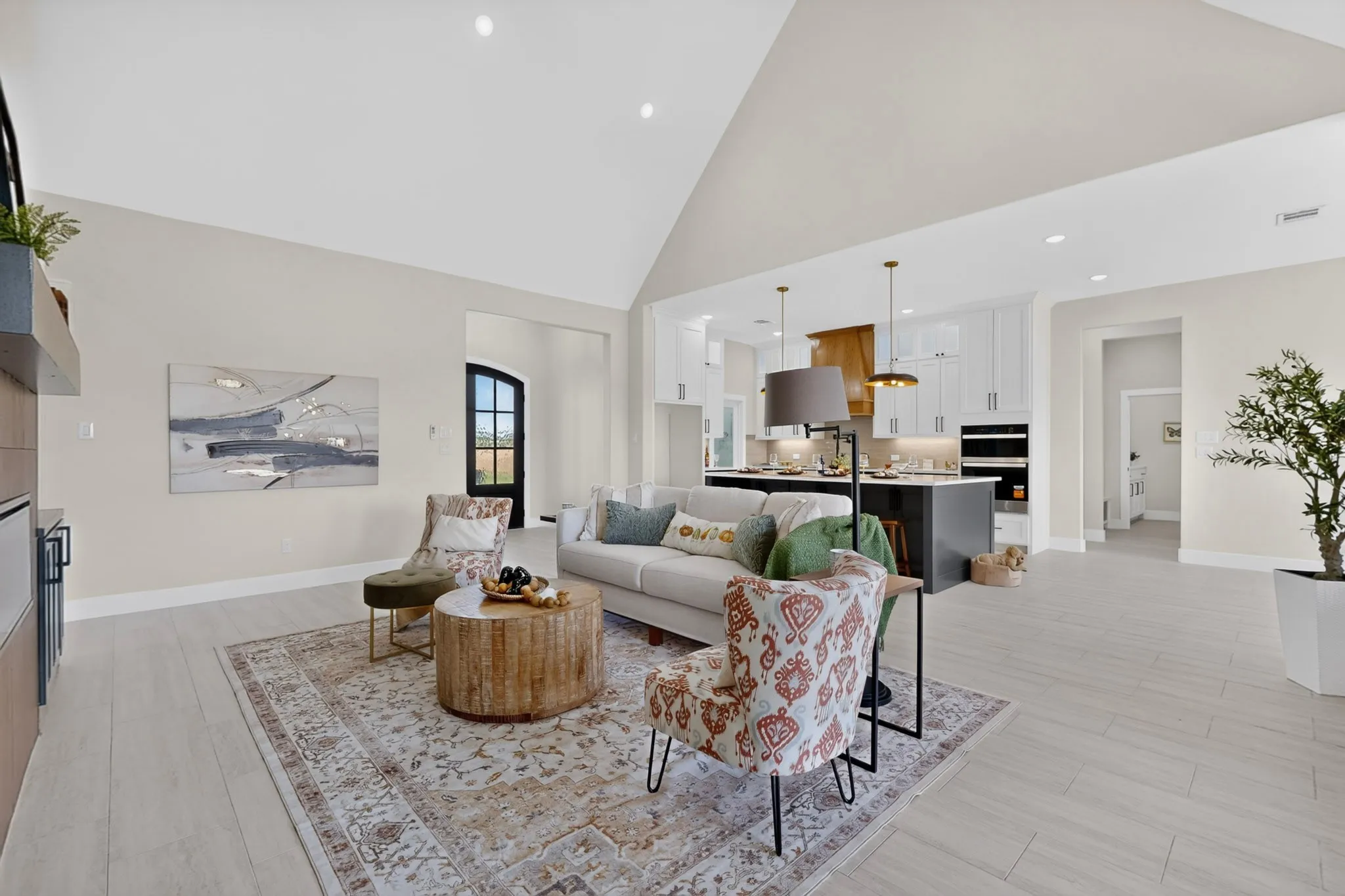 Vaulted ceiling, recessed lighting, light wood-finish flooring, built-in cabinetry with integrated beverage refrigerator, and an arched entryway