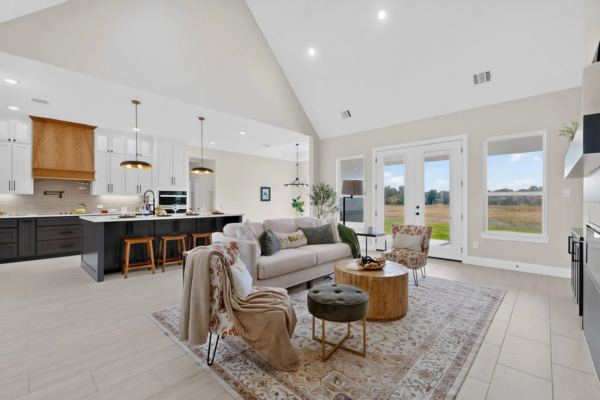 Vaulted ceiling, recessed lighting, wood-finish flooring, kitchen island with counter seating, and double glass doors