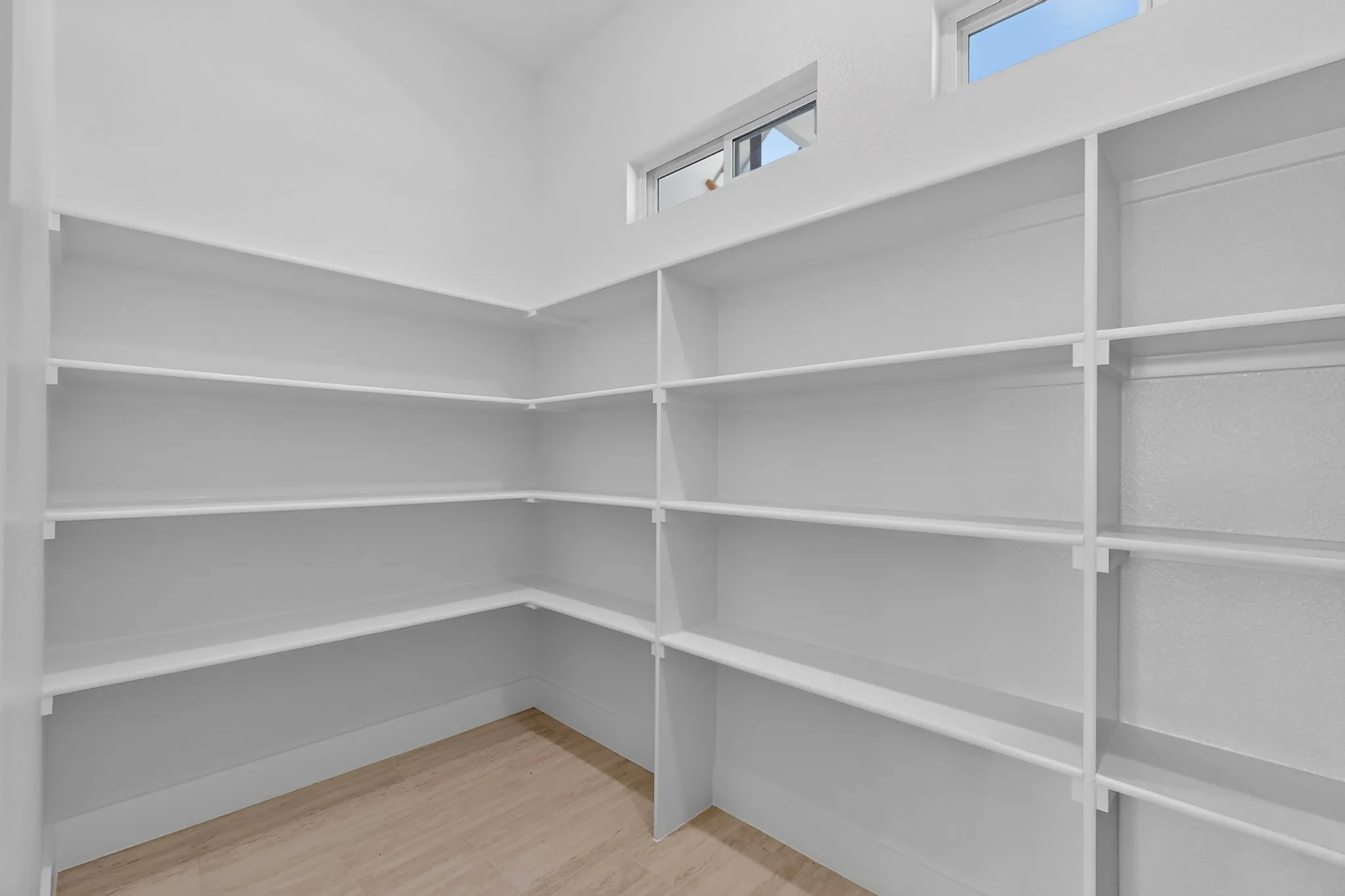 Wraparound shelving with a light wood-finish floor and upper windows