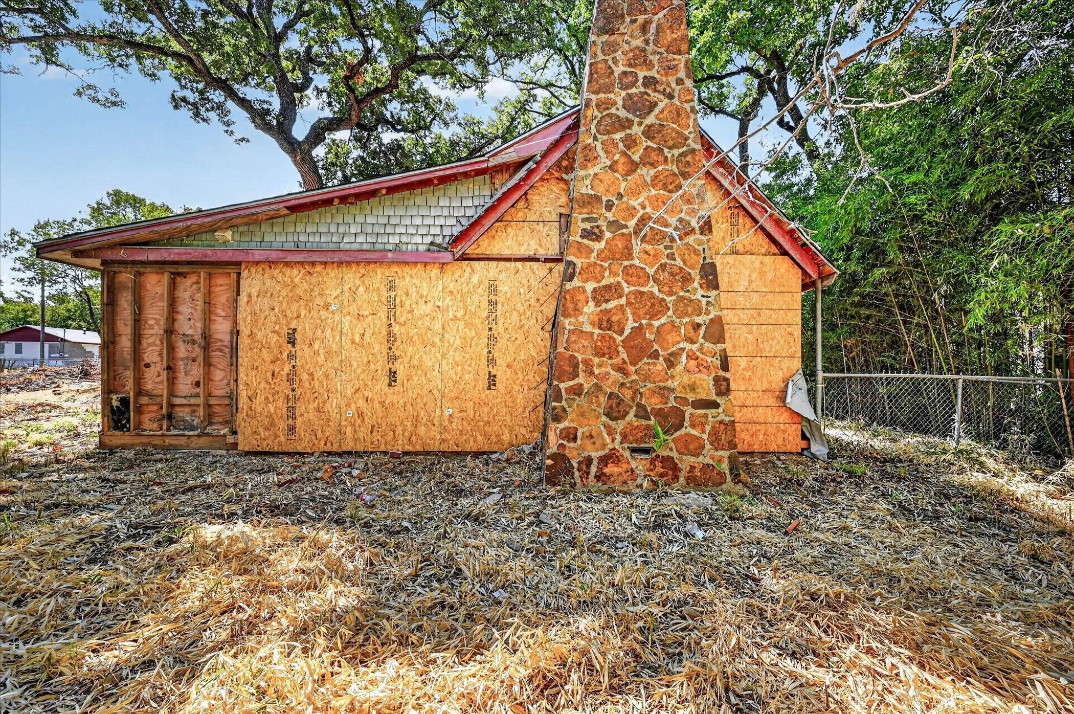Stone-clad chimney, red roofline, wood shingle accents, wood sheathing, natural surroundings