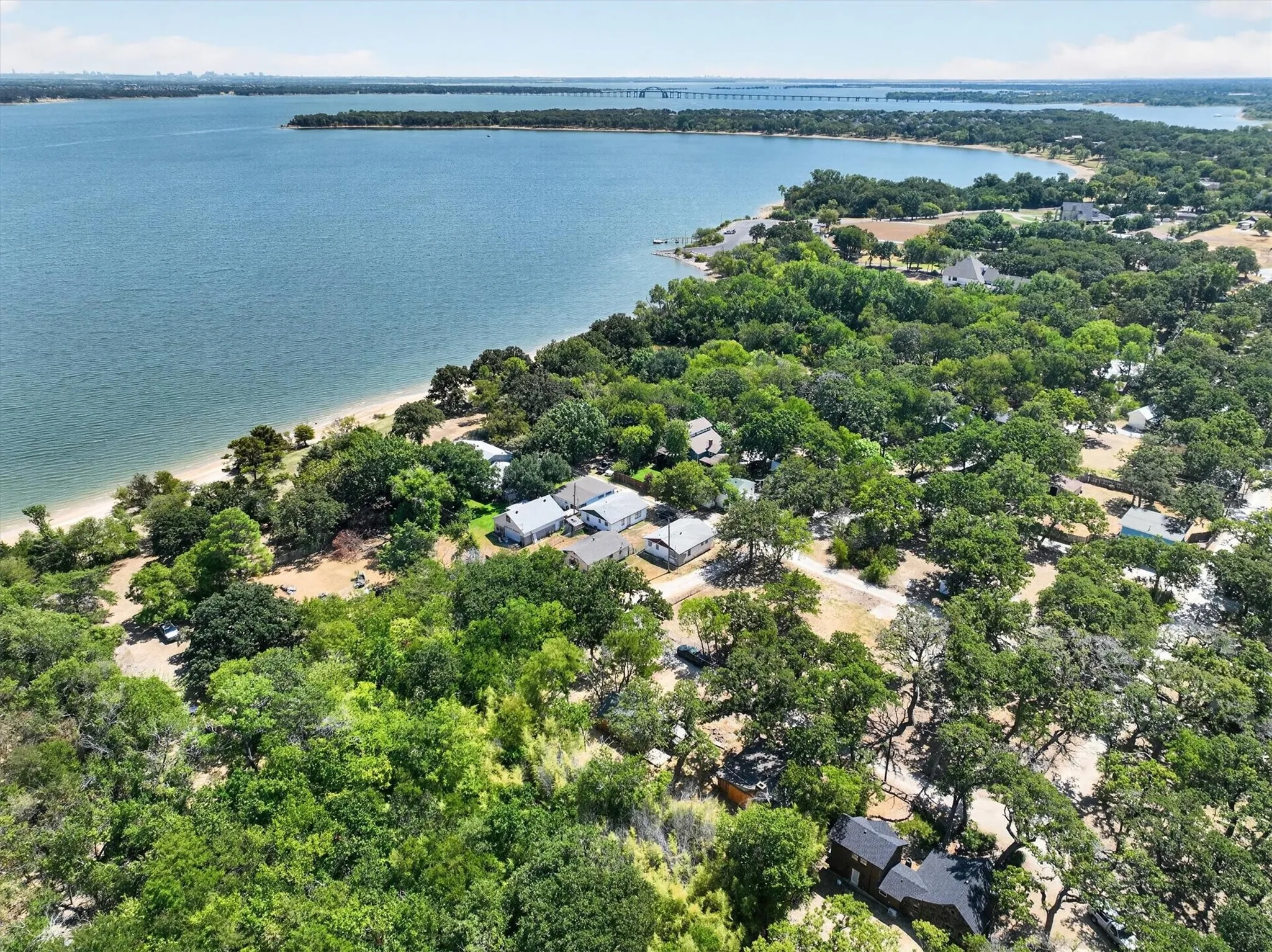 Expansive waterfront property featuring a sandy shoreline and mature trees