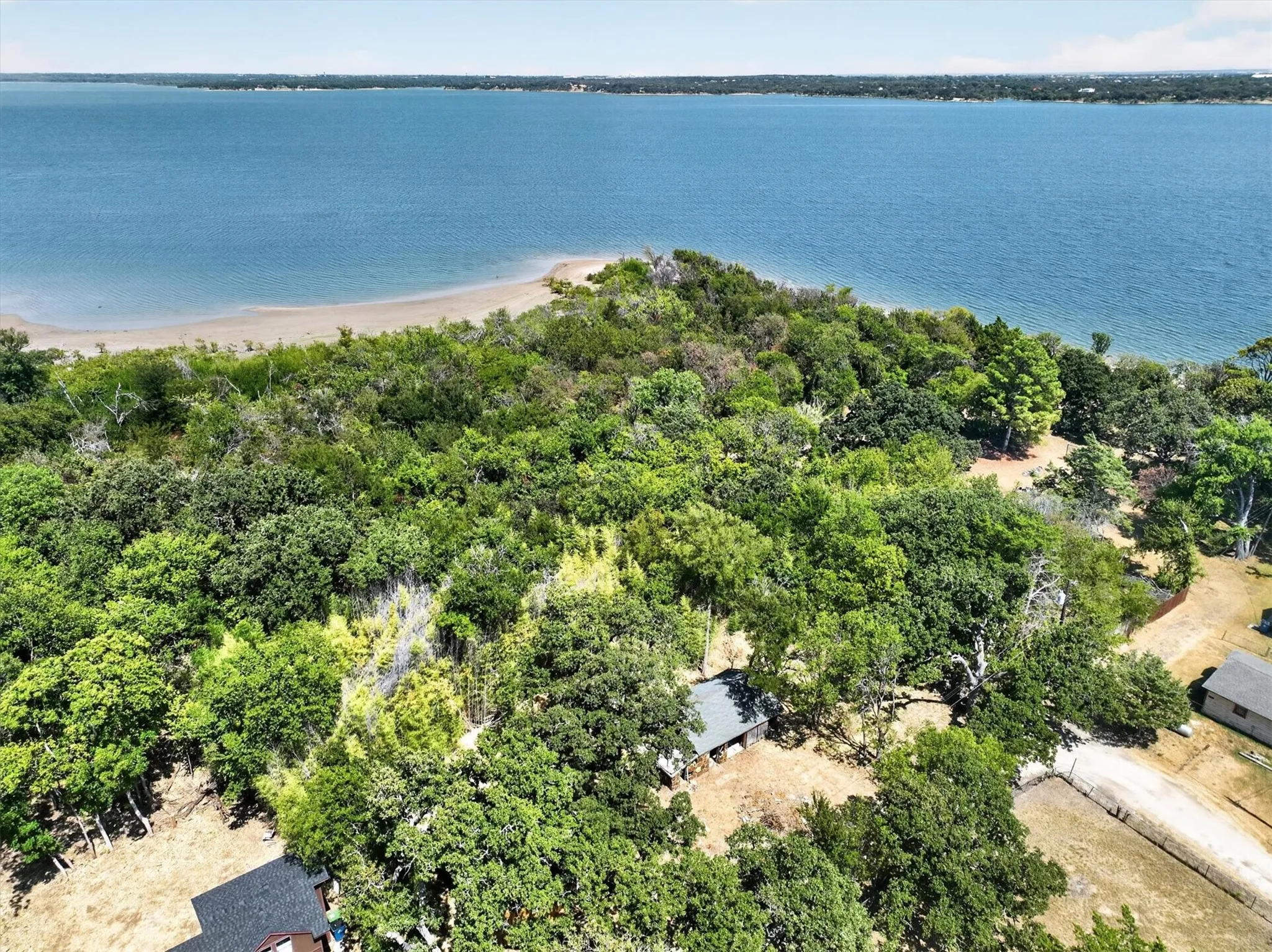 Expansive water frontage with a sandy shoreline, dense mature trees, and a secluded natural setting