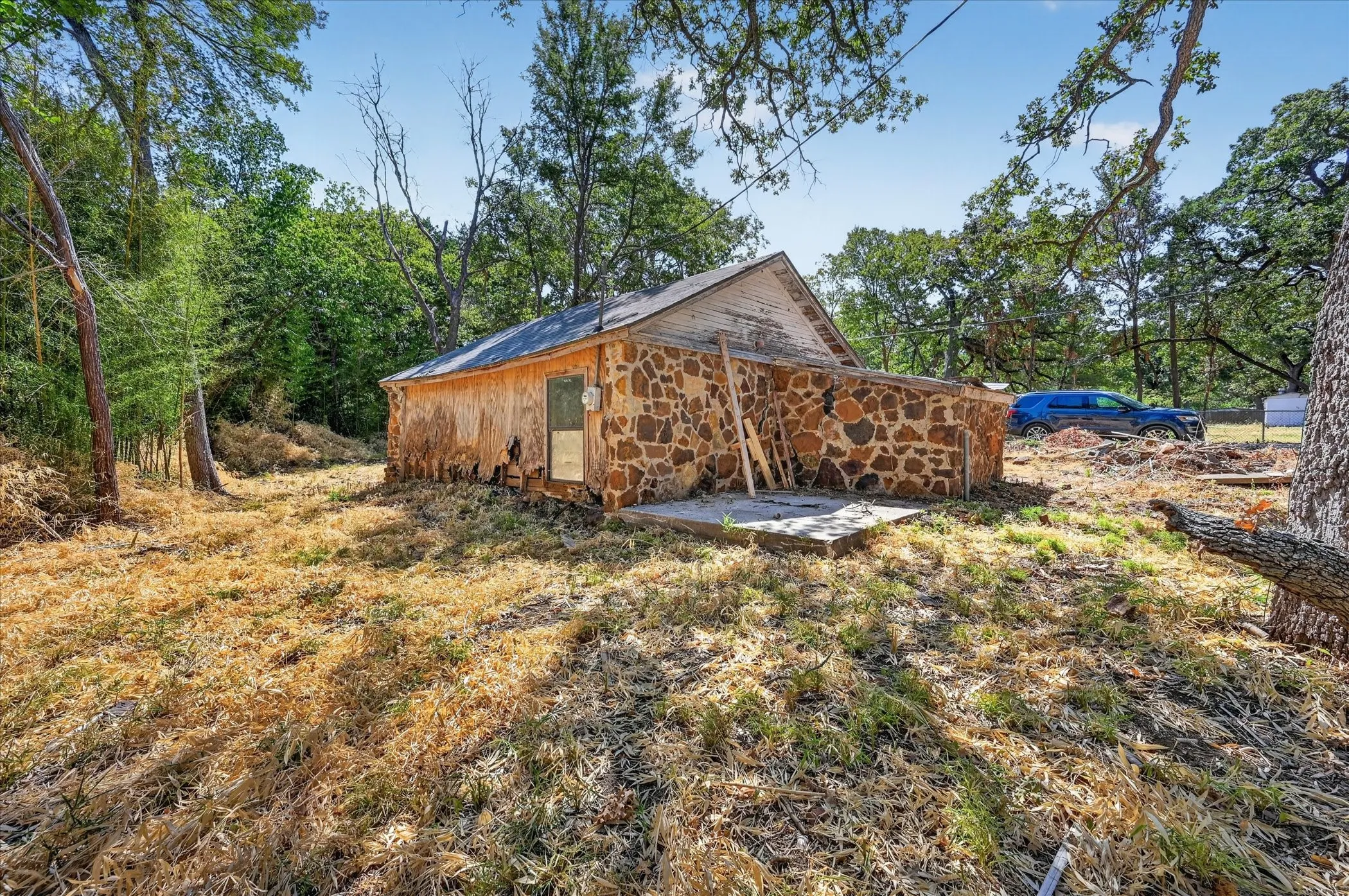 Stone exterior structure with a gabled roof and a concrete pad