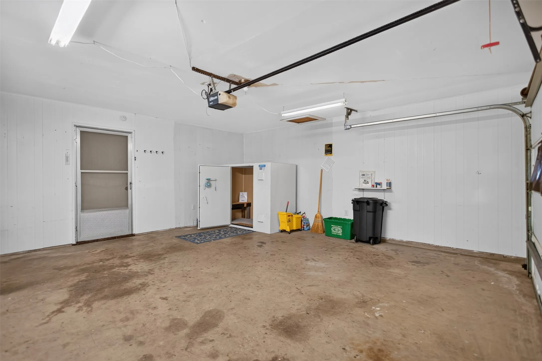 Garage space featuring a concrete floor and white paneling