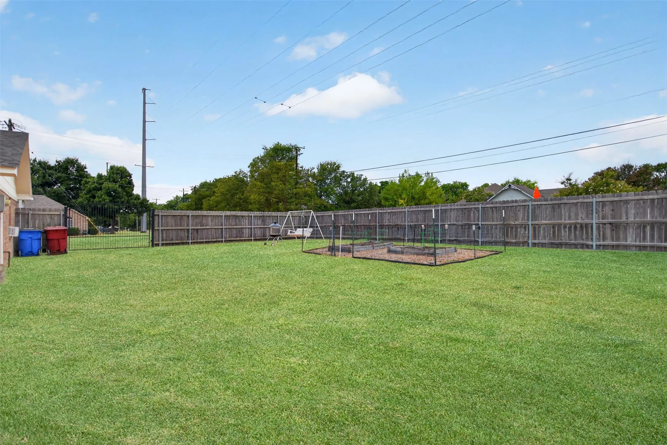 Expansive grass yard with wood fencing and a black metal gate