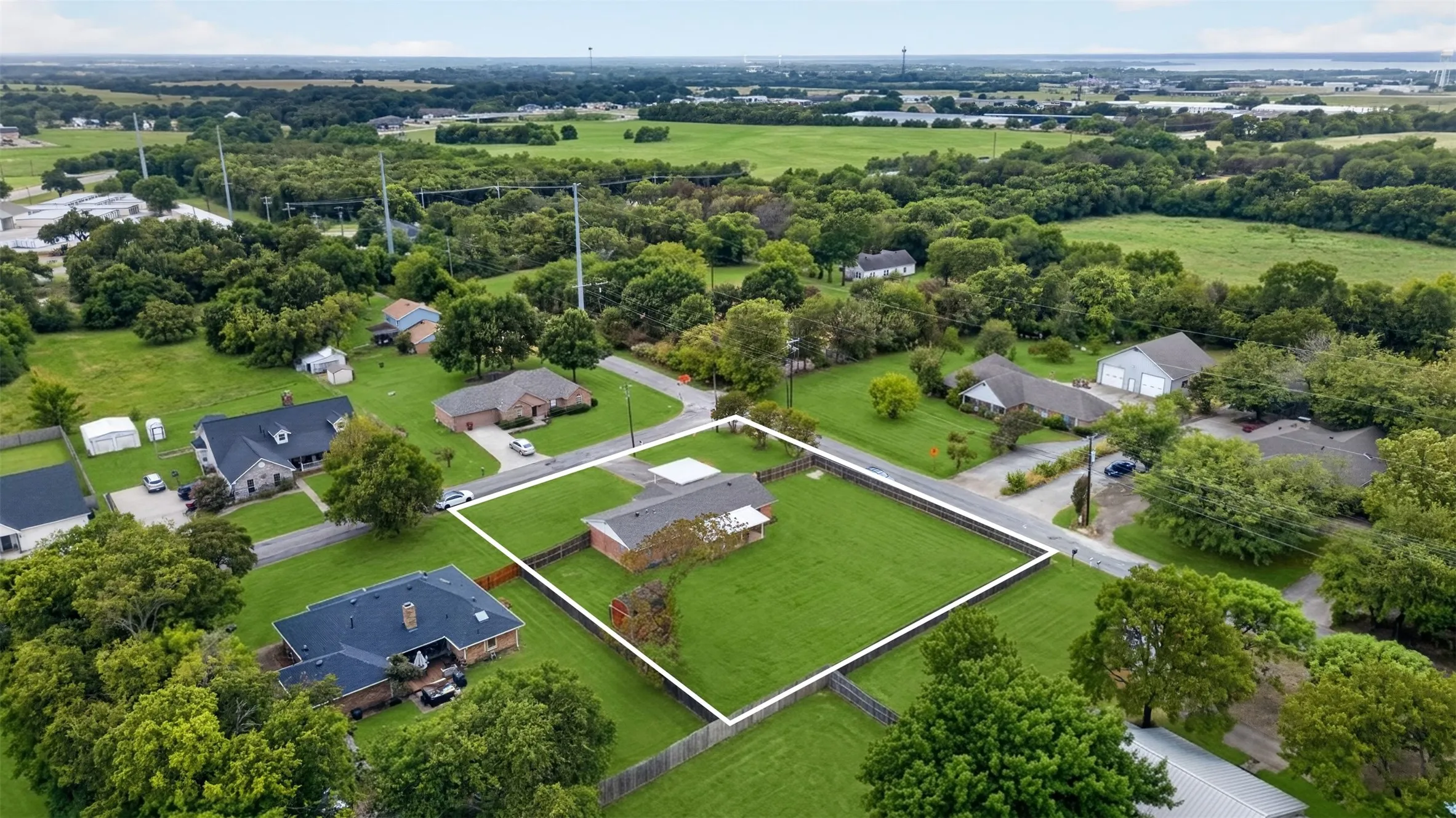 Single-story residence featuring a fenced property, expansive green lawn, and mature trees