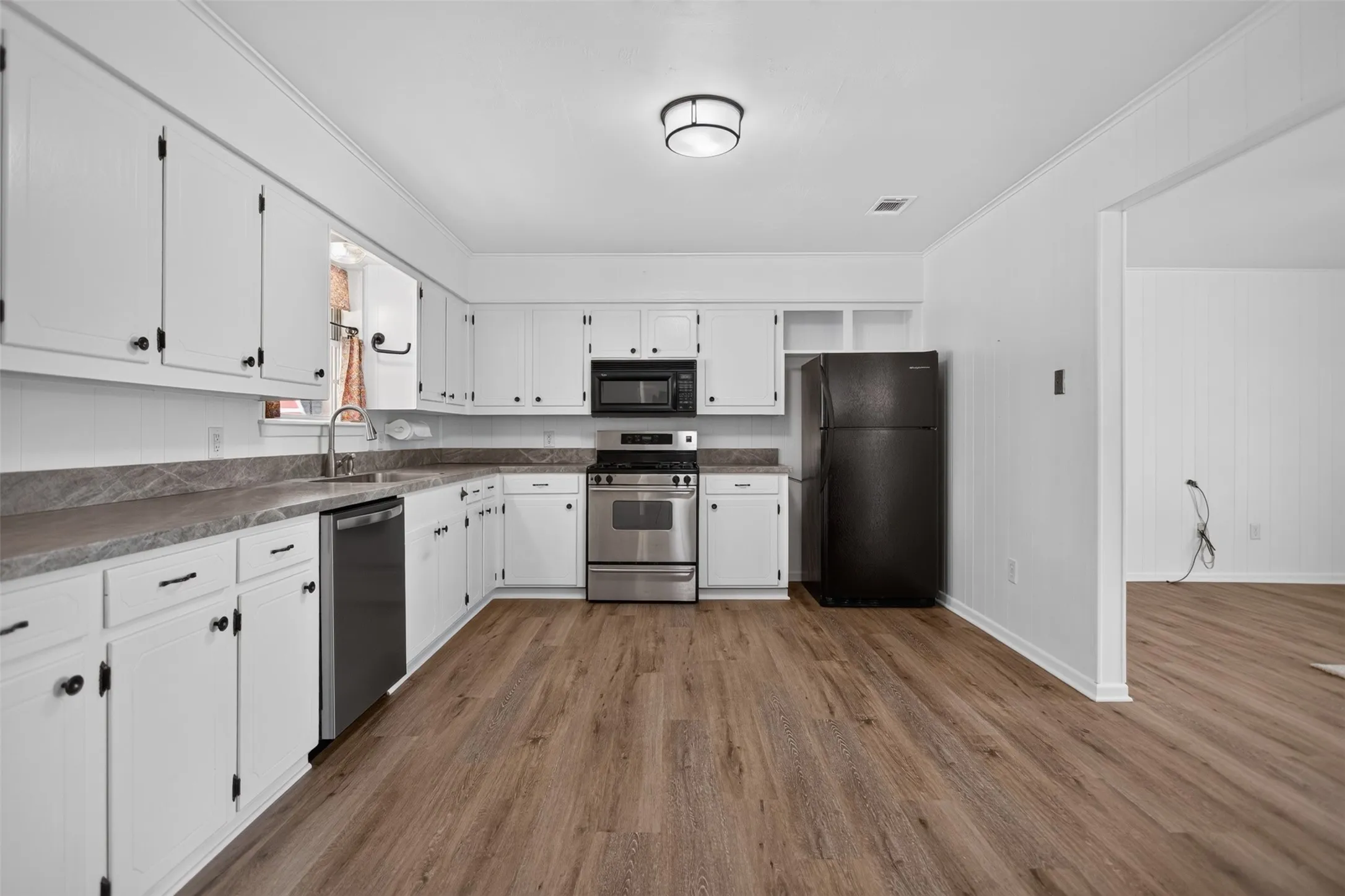 kitchen layout with white cabinetry, stainless steel Gas range, and a built-in microwave