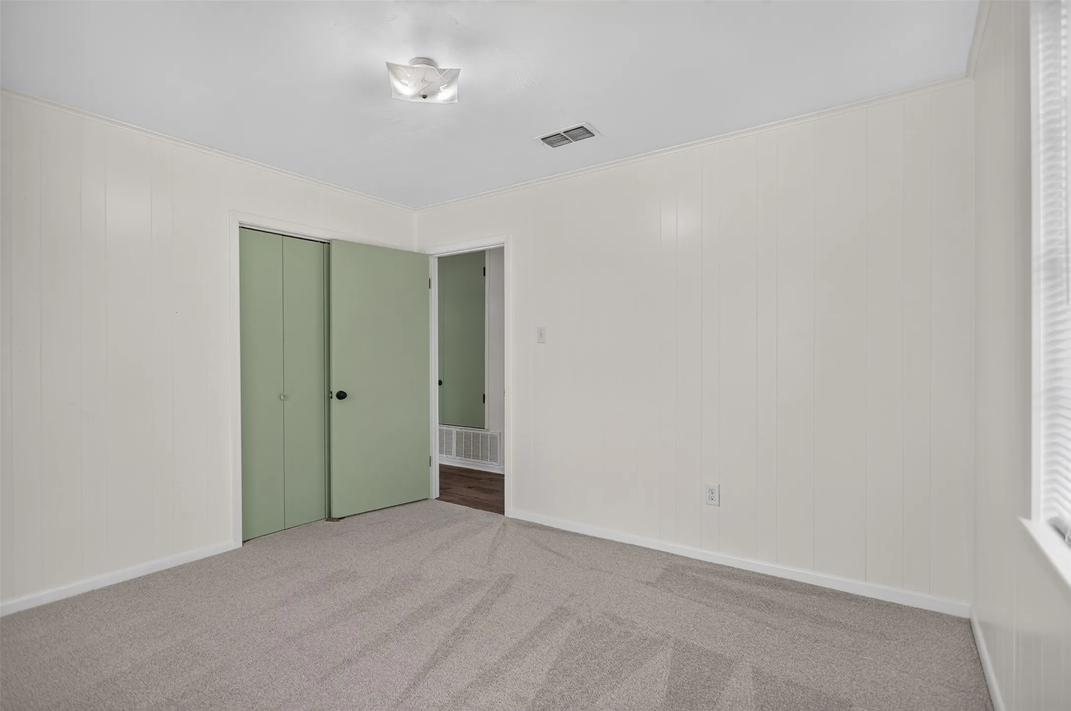 Light gray carpeting, white paneling, and a flush-mount ceiling light fixture
