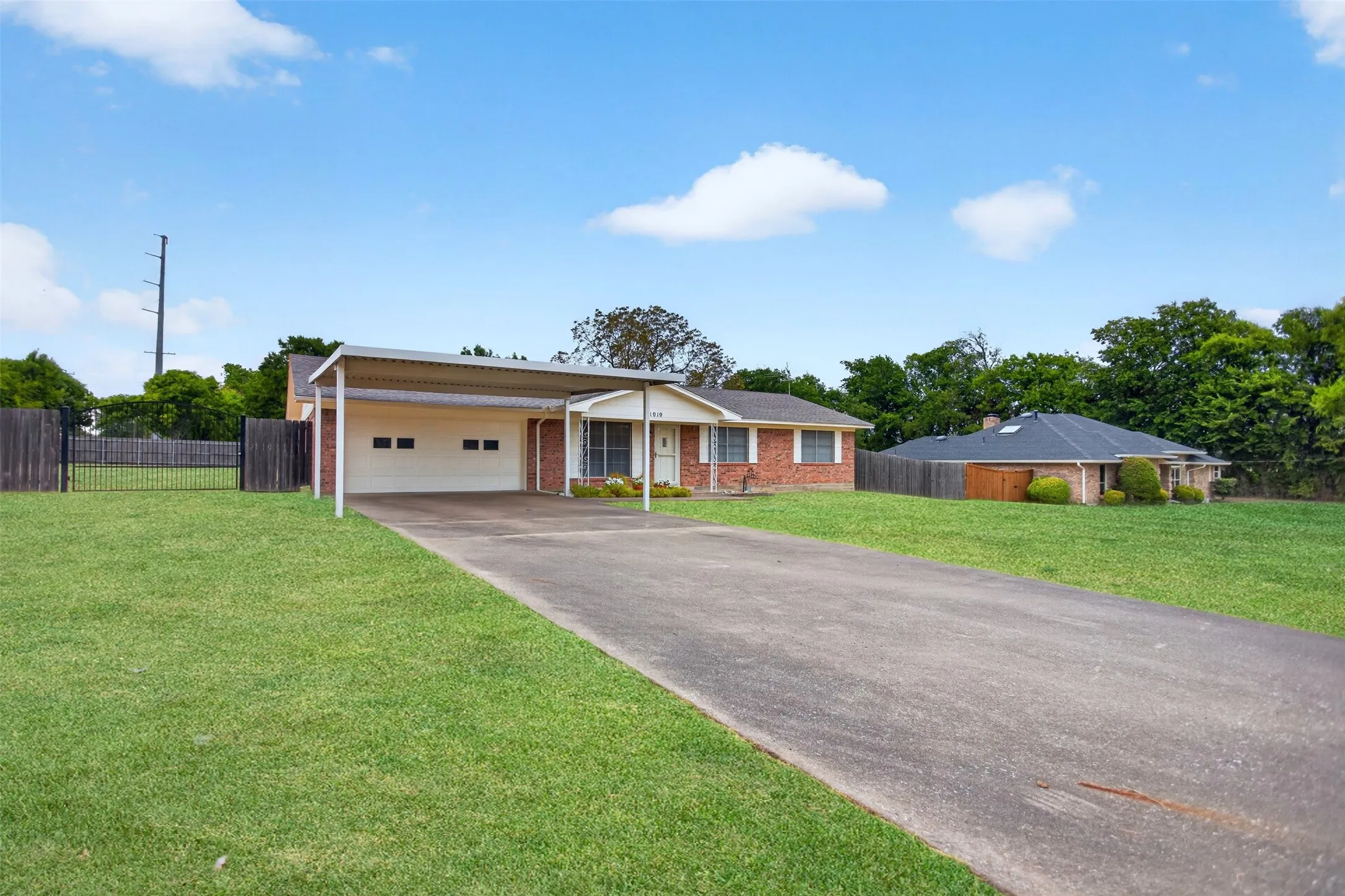 Brick exterior residence with an attached carport, a two-car garage, and a concrete driveway