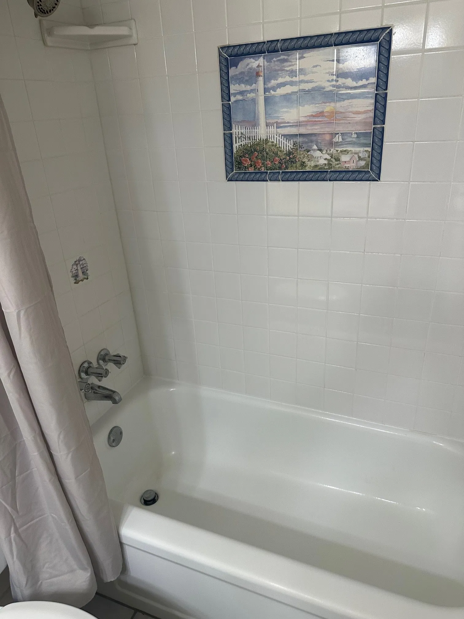 White tiled shower surround with a built-in corner shelf and polished chrome fixtures