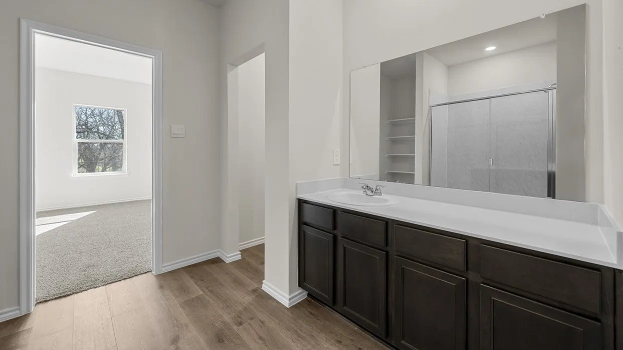Dual vanity with dark wood-finish cabinetry, light-toned countertop, and integrated sink