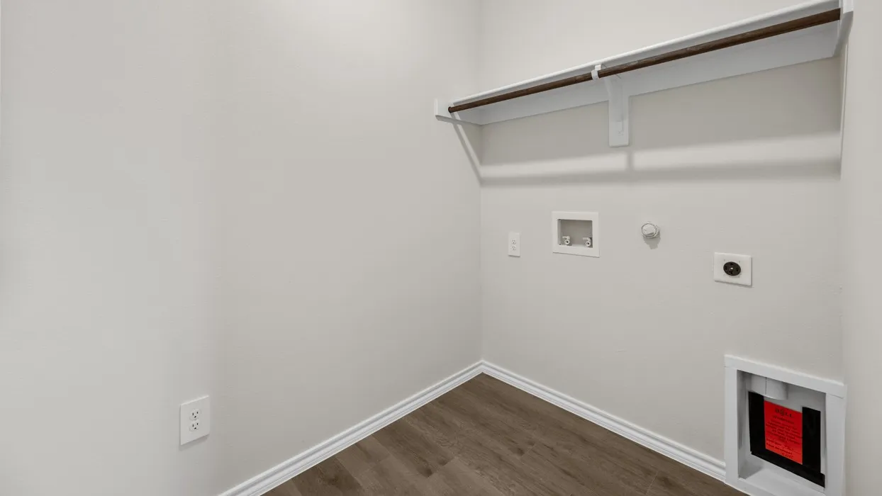 Laundry area featuring wood-finish flooring, a wall-mounted shelf, and a clothing rod
