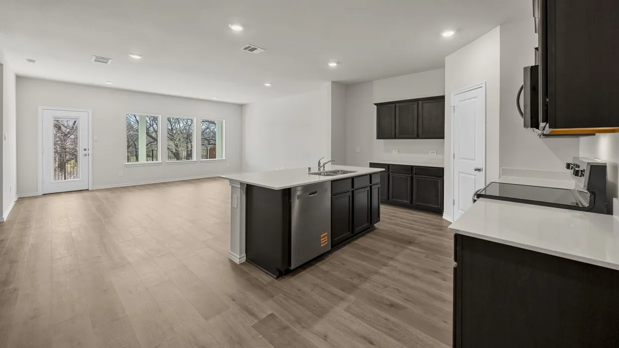 Open-concept living space with wood-finish flooring, a kitchen island, white countertops, dark cabinetry, and recessed lighting