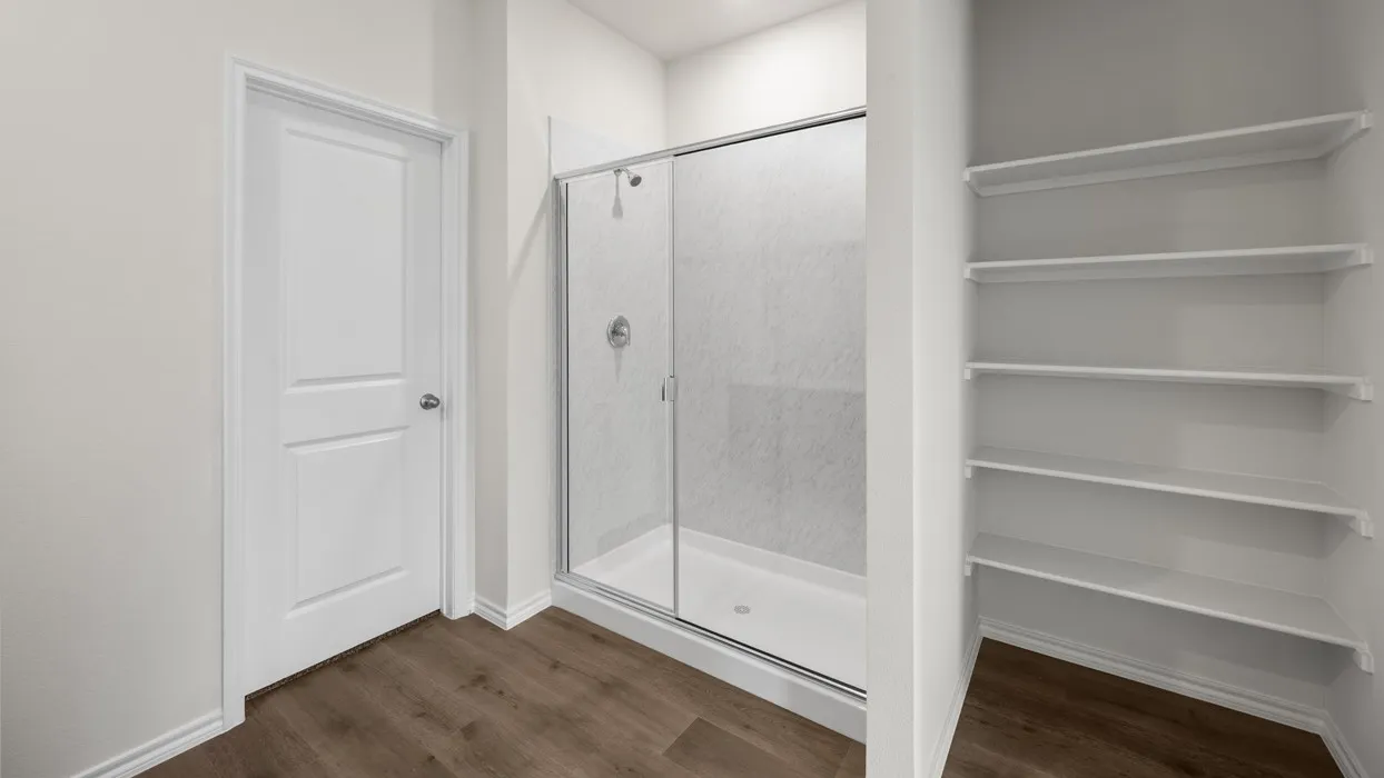 Walk-in shower with a glass enclosure, a dedicated storage alcove with multiple shelves, and wood-finish flooring