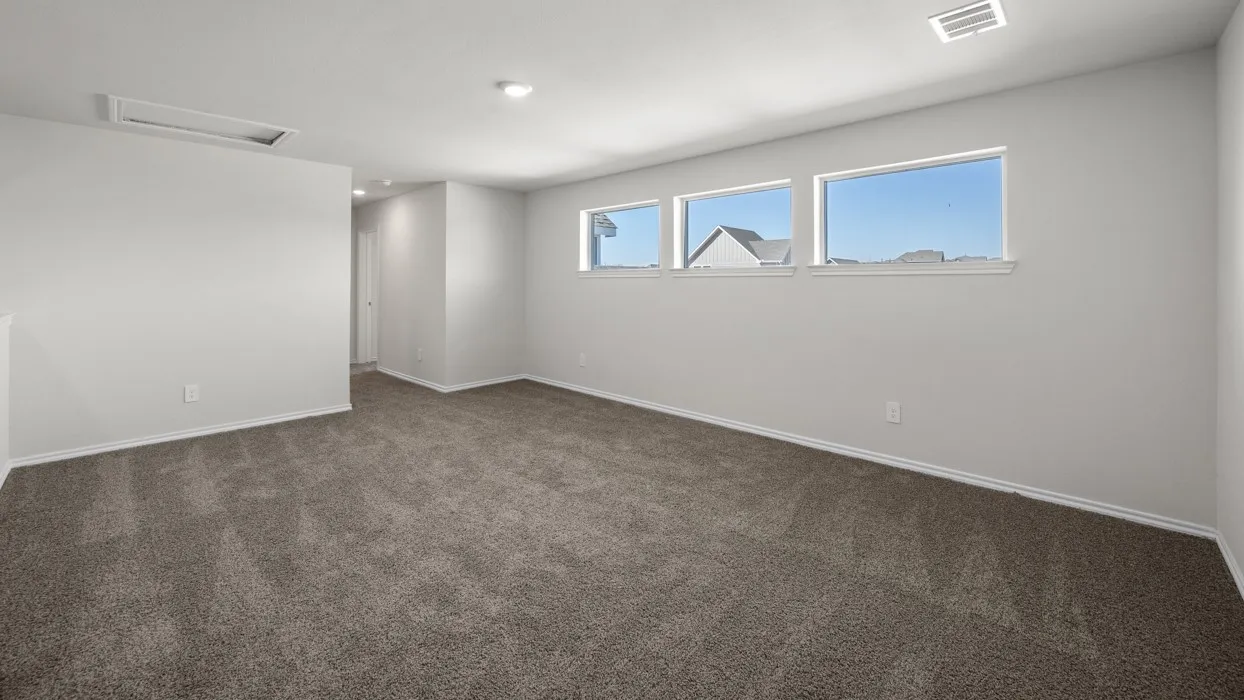 Spacious room featuring neutral carpeting, light-colored walls, and a series of three windows