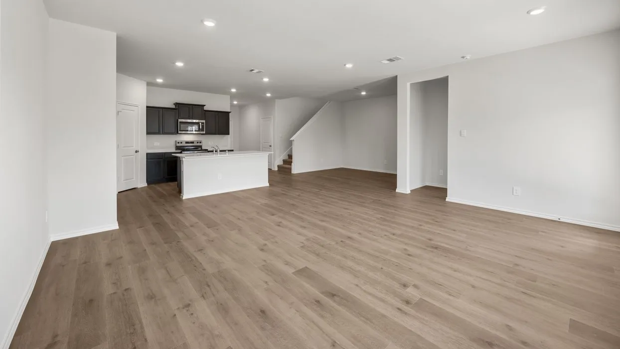 Open-concept living area featuring wood-finish flooring, recessed lighting, and a kitchen island with seating