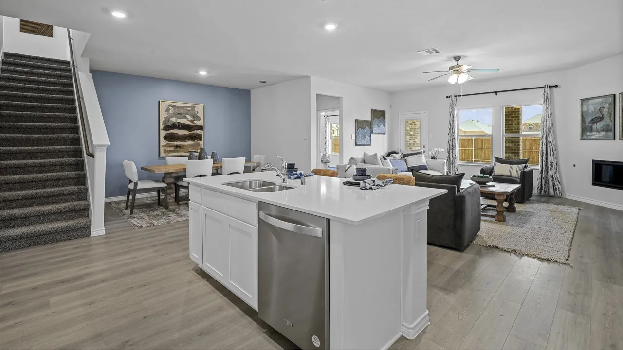 Spacious open concept living area featuring wood-finish flooring, a kitchen island with a built-in stainless steel dishwasher, an integrated kitchen sink, and a ceiling fan