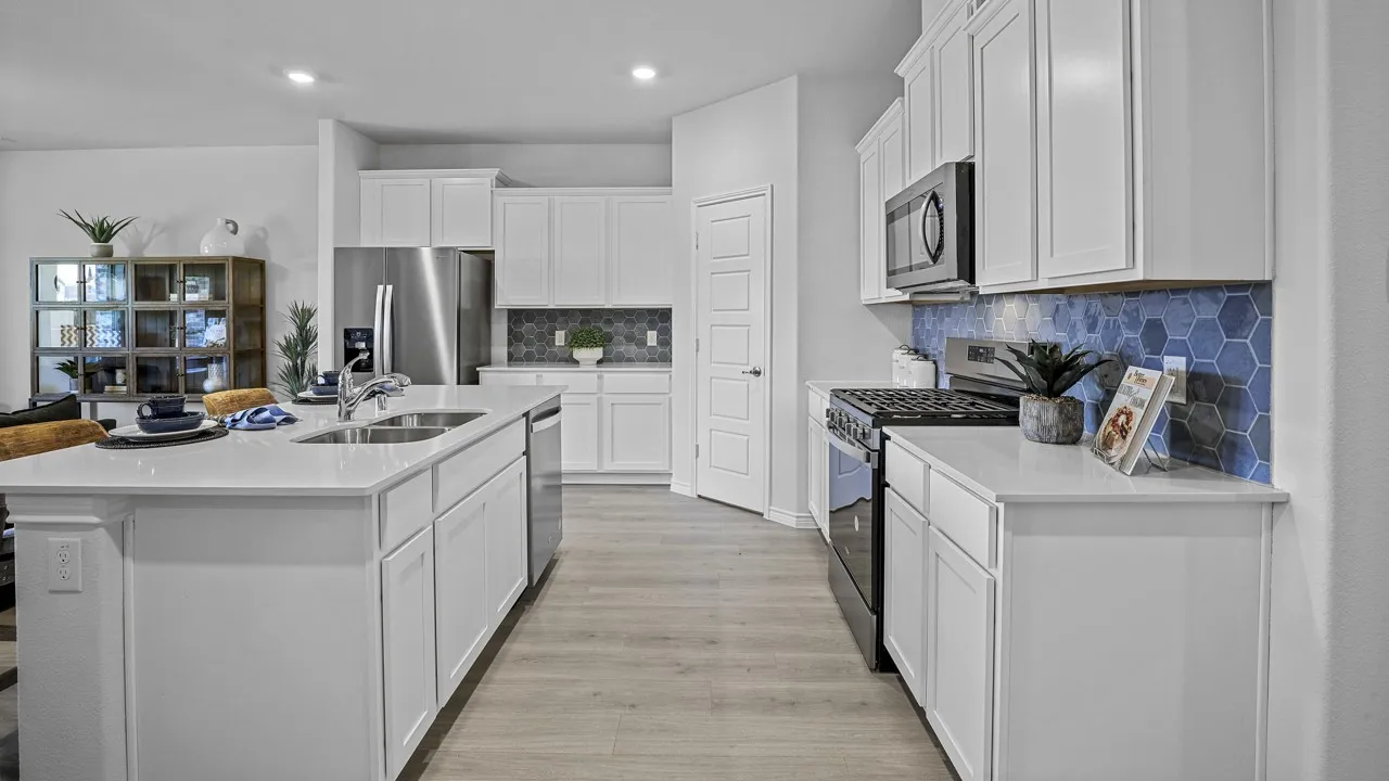 Kitchen featuring white cabinetry, light-toned wood-finish flooring, stainless steel appliances, and a blue hexagonal tile backsplash