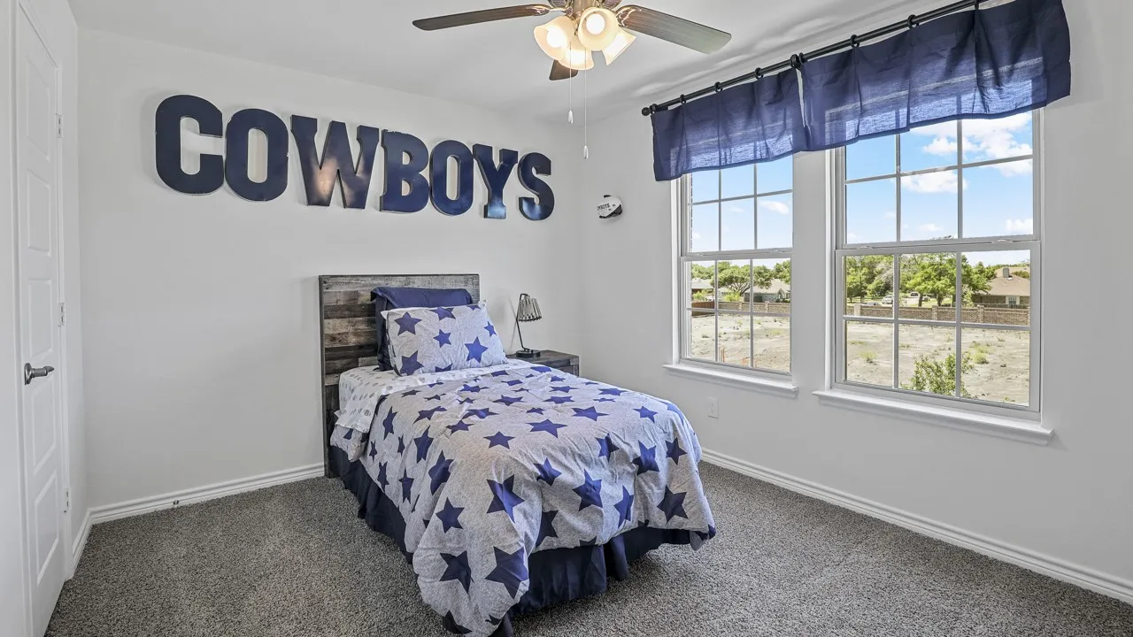 White wall paint, gray carpet flooring, two double-hung windows, and a ceiling fan with light fixture