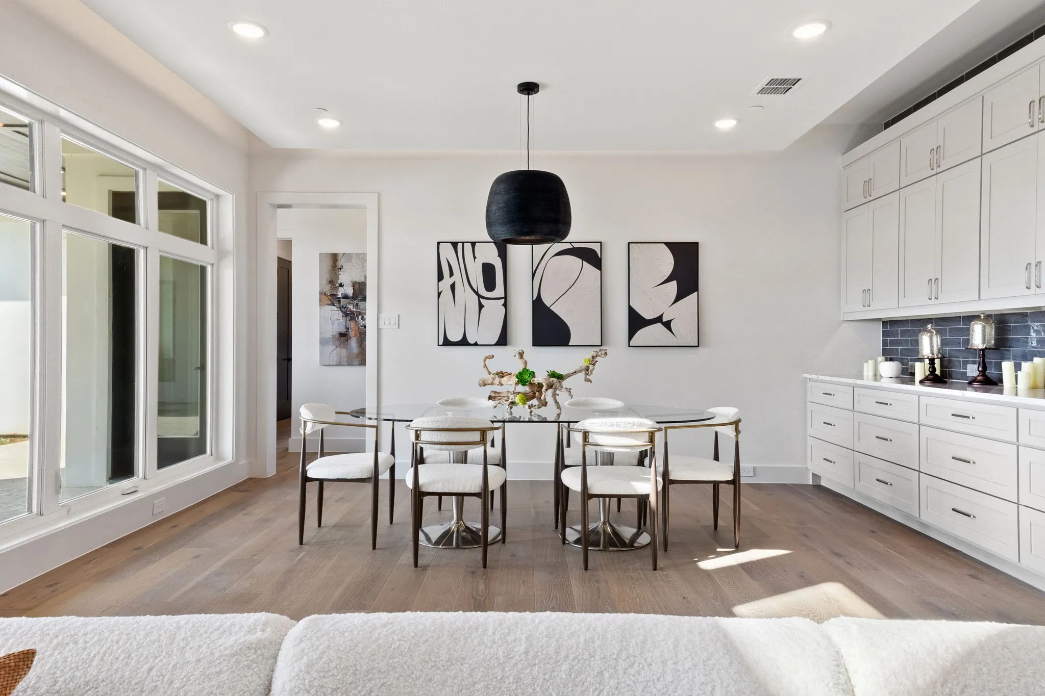 Expansive window wall, recessed lighting, wood-finish flooring, white cabinetry, and a dark tile backsplash