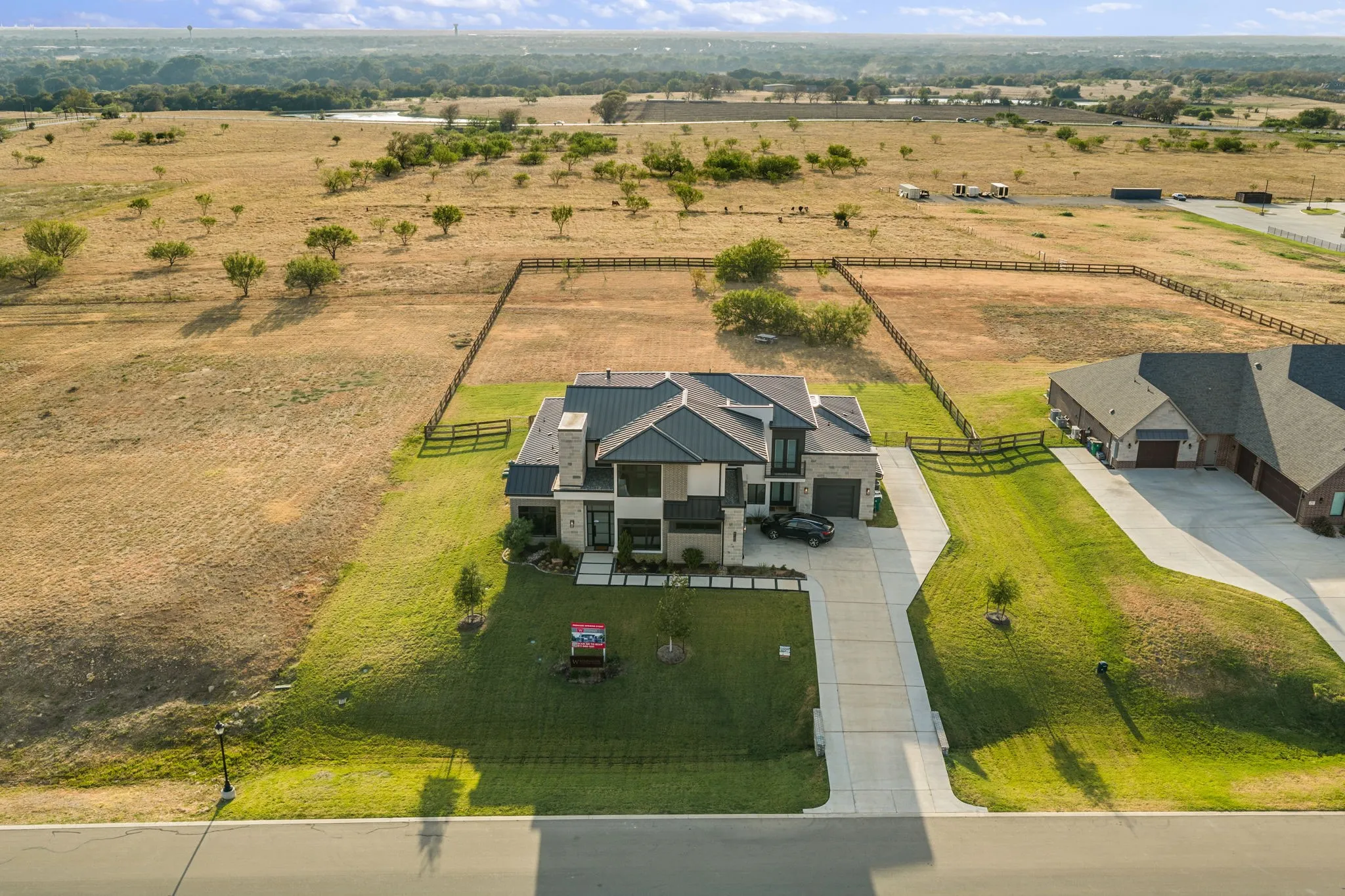 Contemporary exterior with stone accents, a dark-colored roof, and an expansive concrete driveway