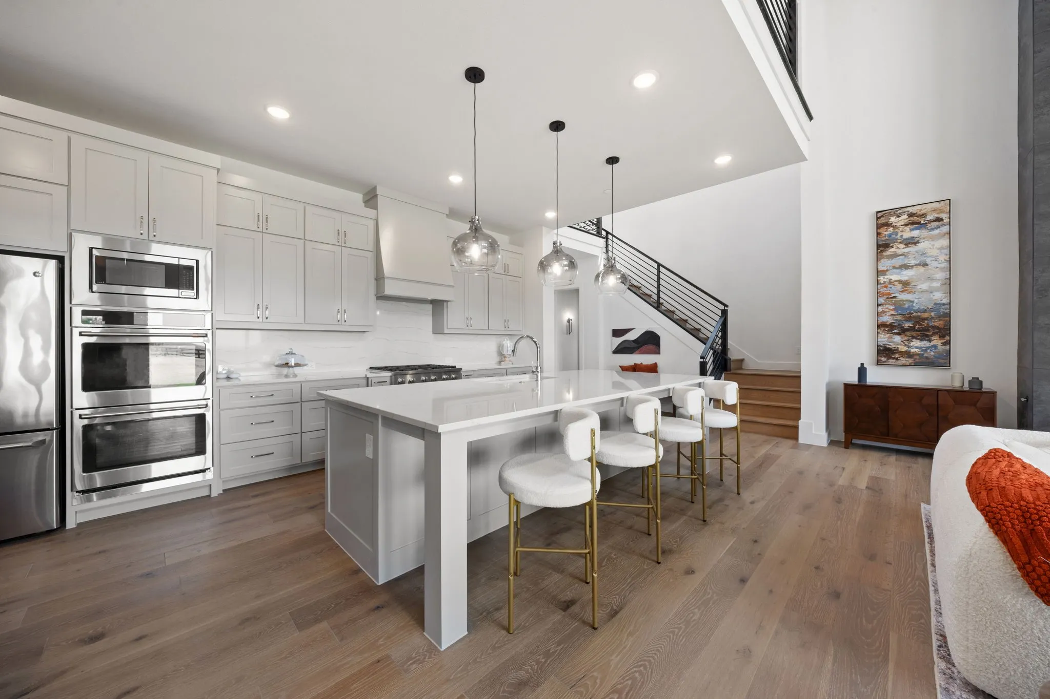 Gourmet kitchen with stainless steel appliances, light wood-finish flooring, and a large center island with pendant lighting
