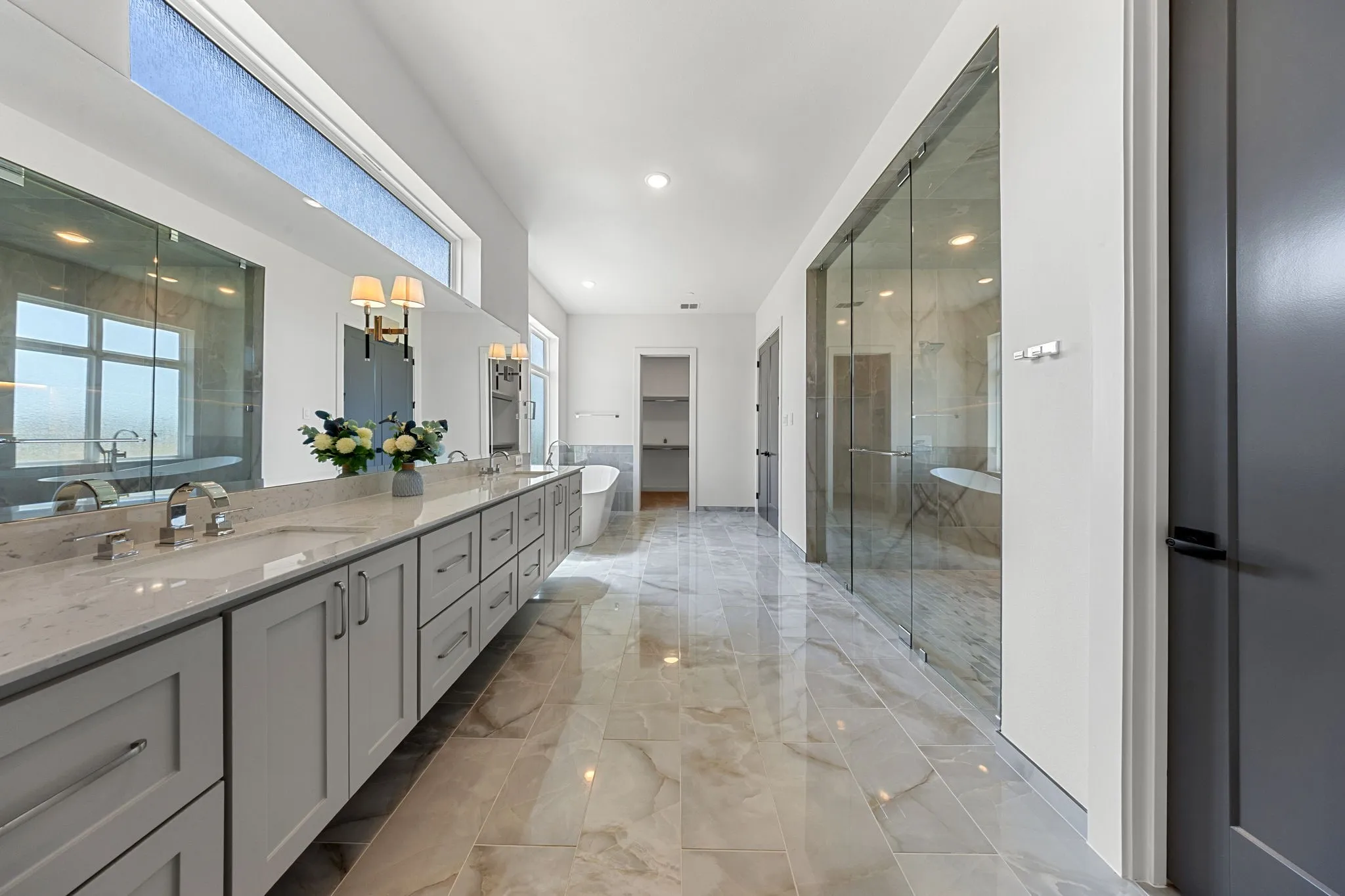 Spa-inspired primary bathroom featuring a dual-sink vanity with soft-close cabinetry, polished stone countertops, and chrome fixtures