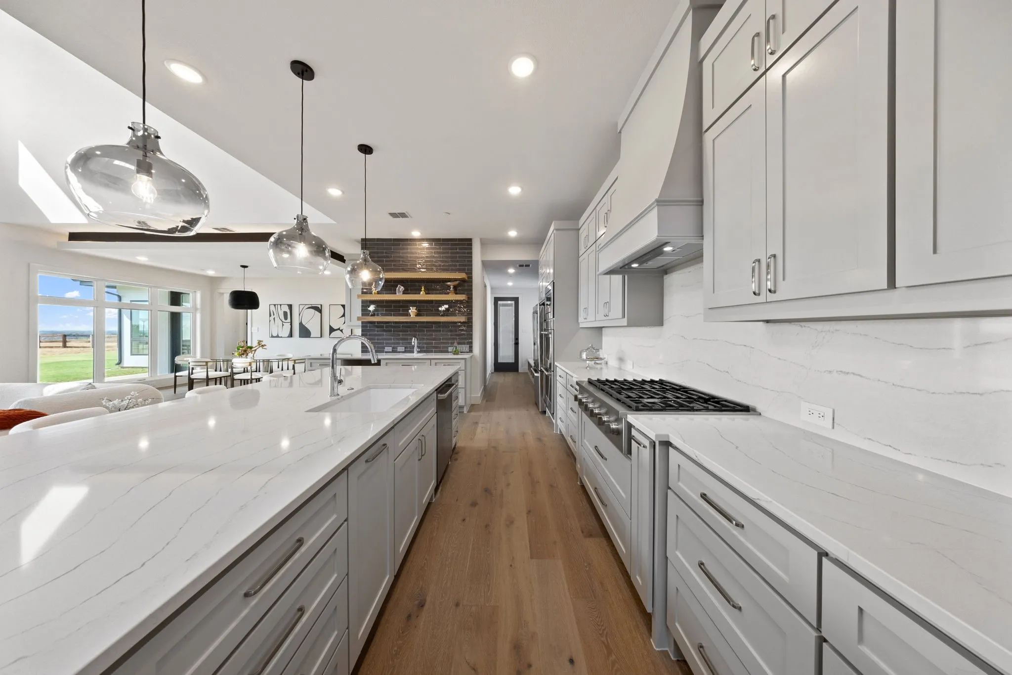 Gourmet kitchen featuring a gas range, built-in appliances, a large center island with an undermount sink, and extensive cabinetry with modern hardware