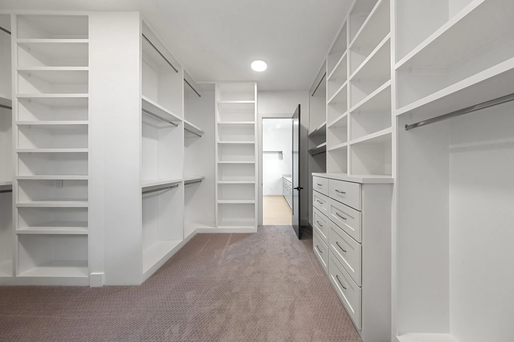 Built-in shelving and hanging rods with a built-in dresser featuring multiple drawers and metal hardware