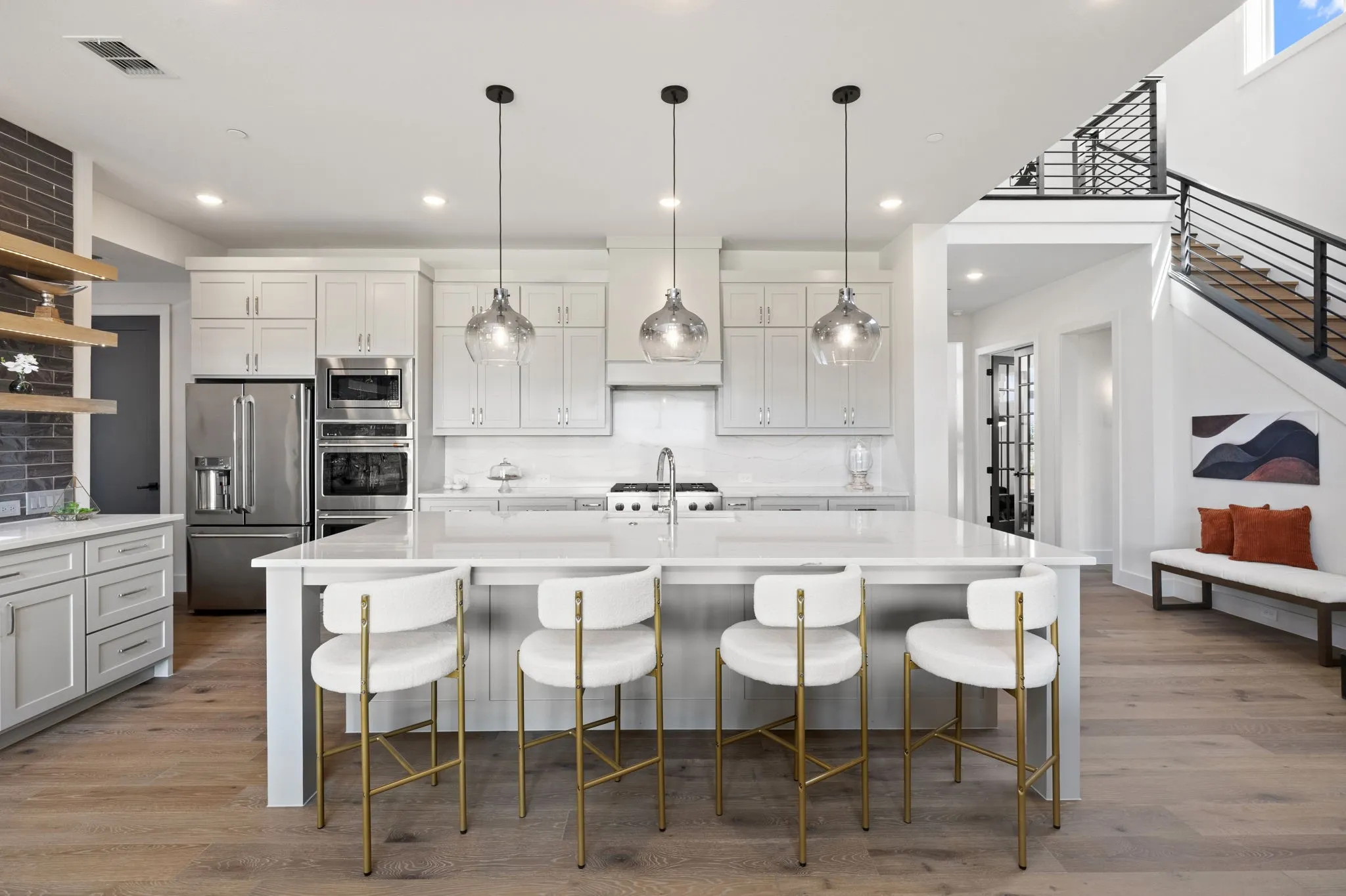 Gourmet kitchen with stainless steel appliances, large center island, pendant lighting, and wood-finish flooring
