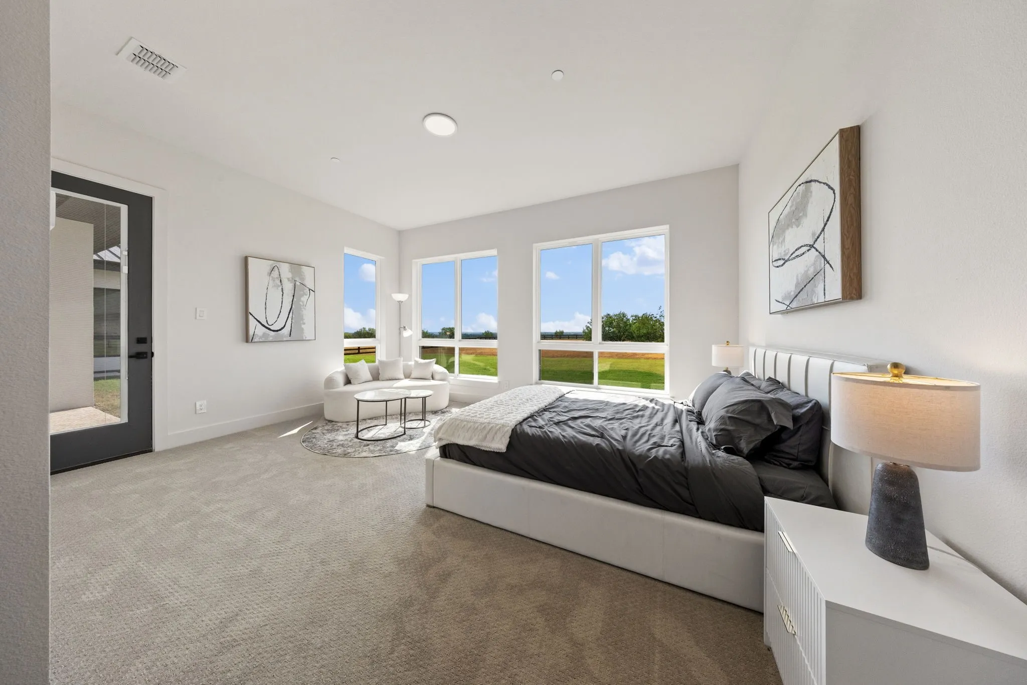 Spacious carpeted room featuring a dark-framed glass paneled door, multiple large windows, and recessed lighting