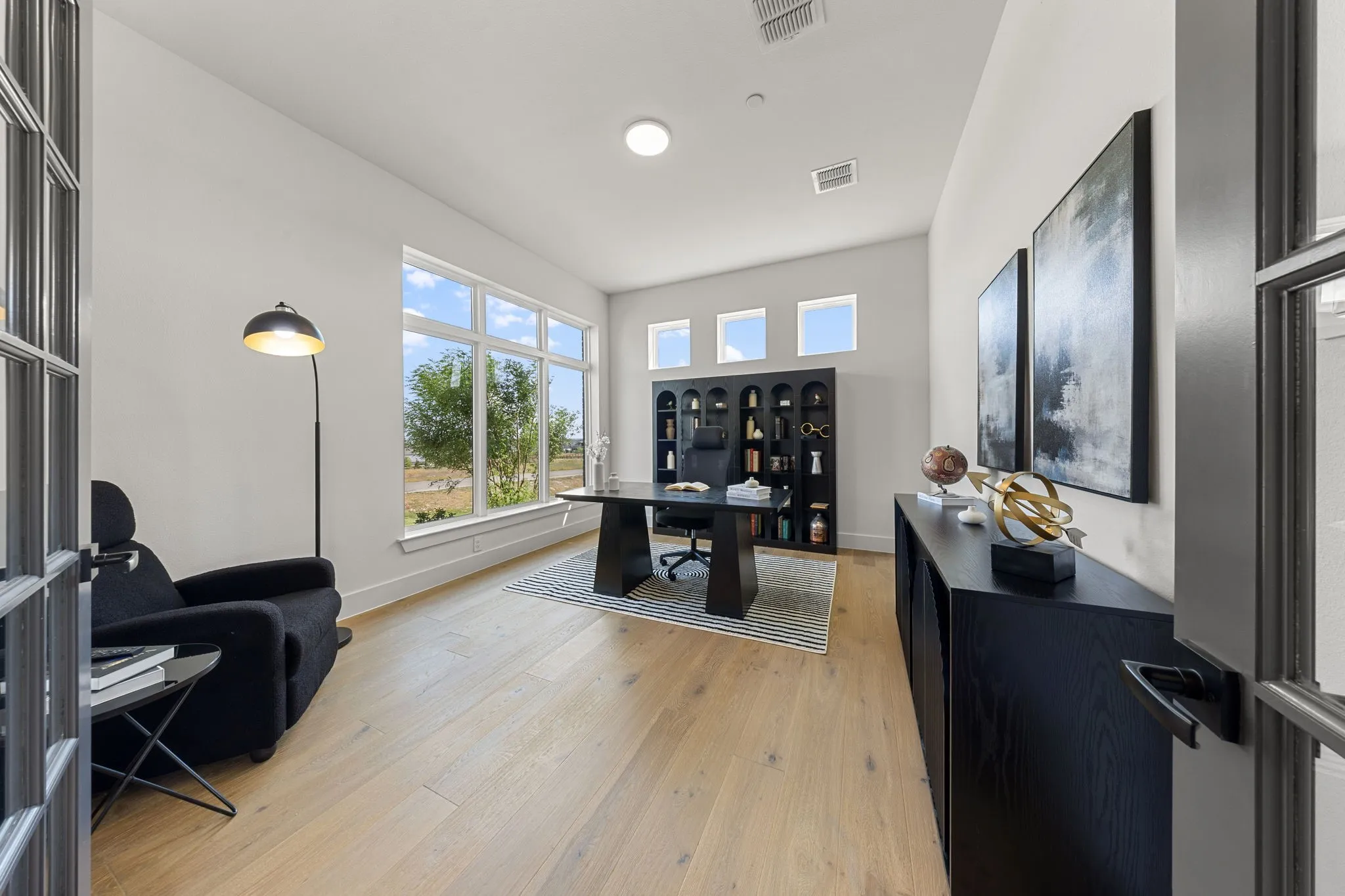 Bright interior featuring wood-finish flooring, a large multi-pane window, recessed lighting, and built-in shelving