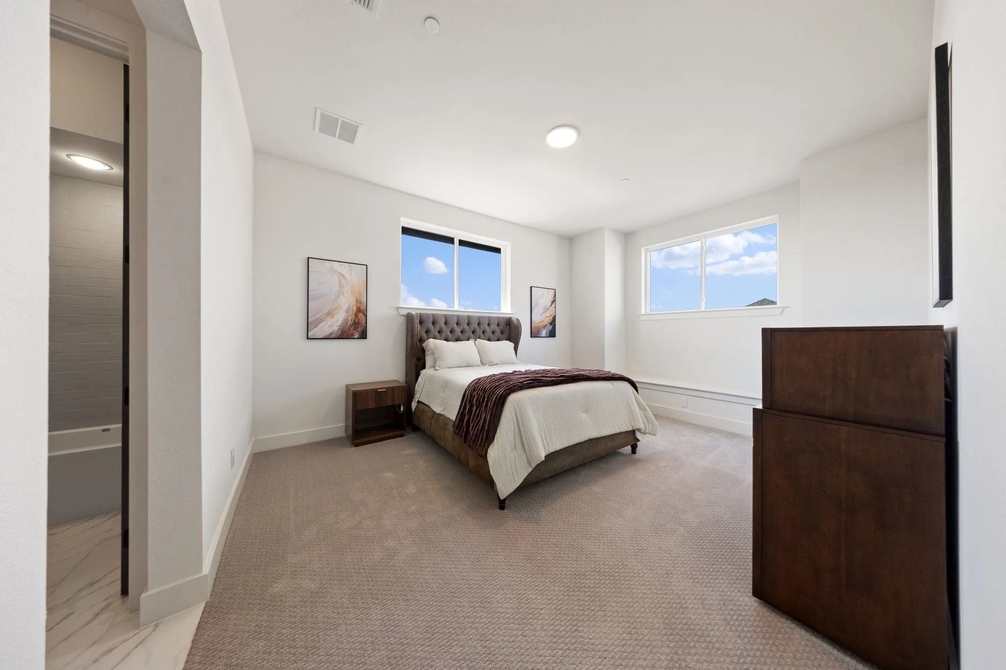 Plush carpet flooring, recessed ceiling lighting, and multiple windows providing ambient light