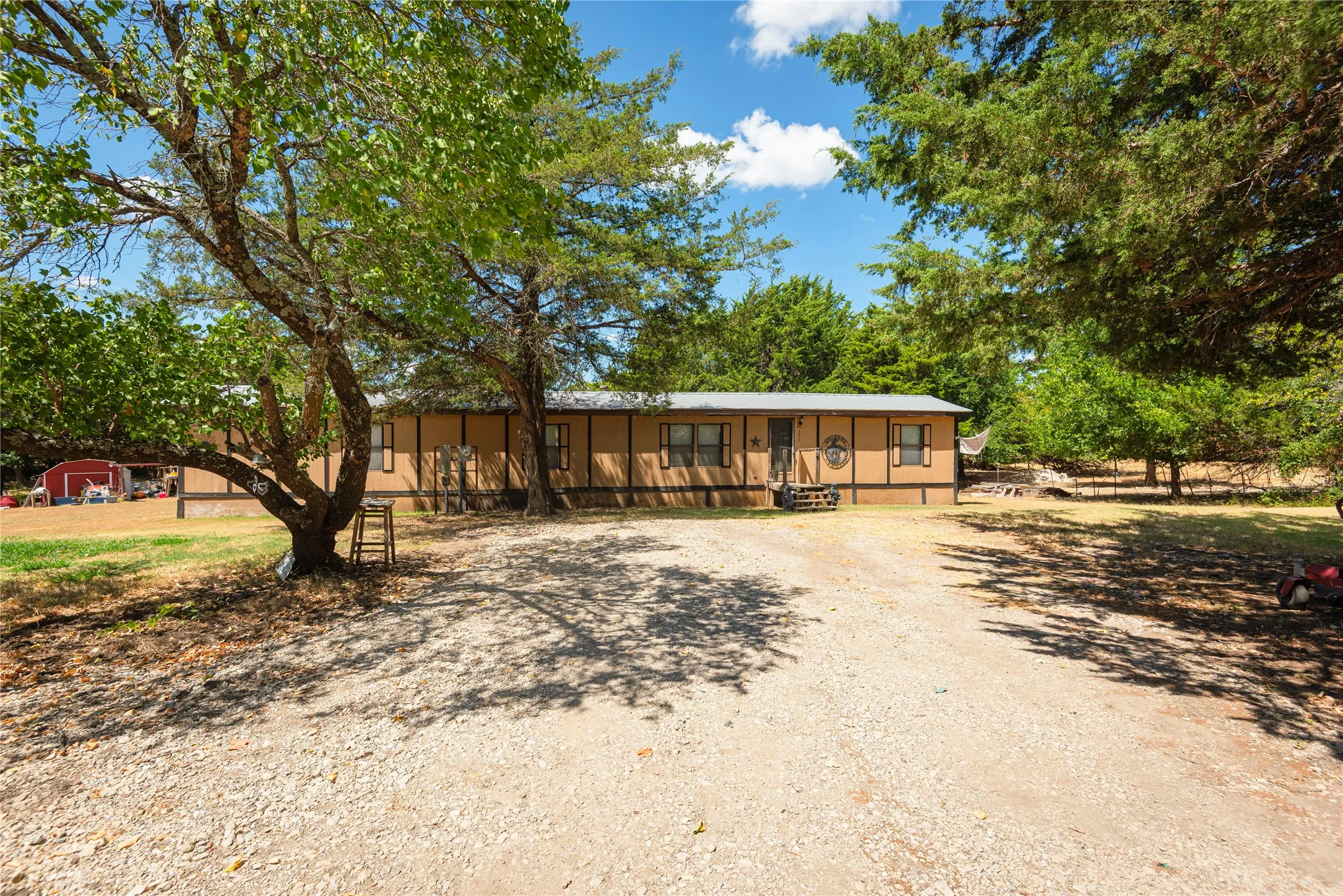 Single-story residence with a covered entry, dark-framed windows, and a gravel driveway