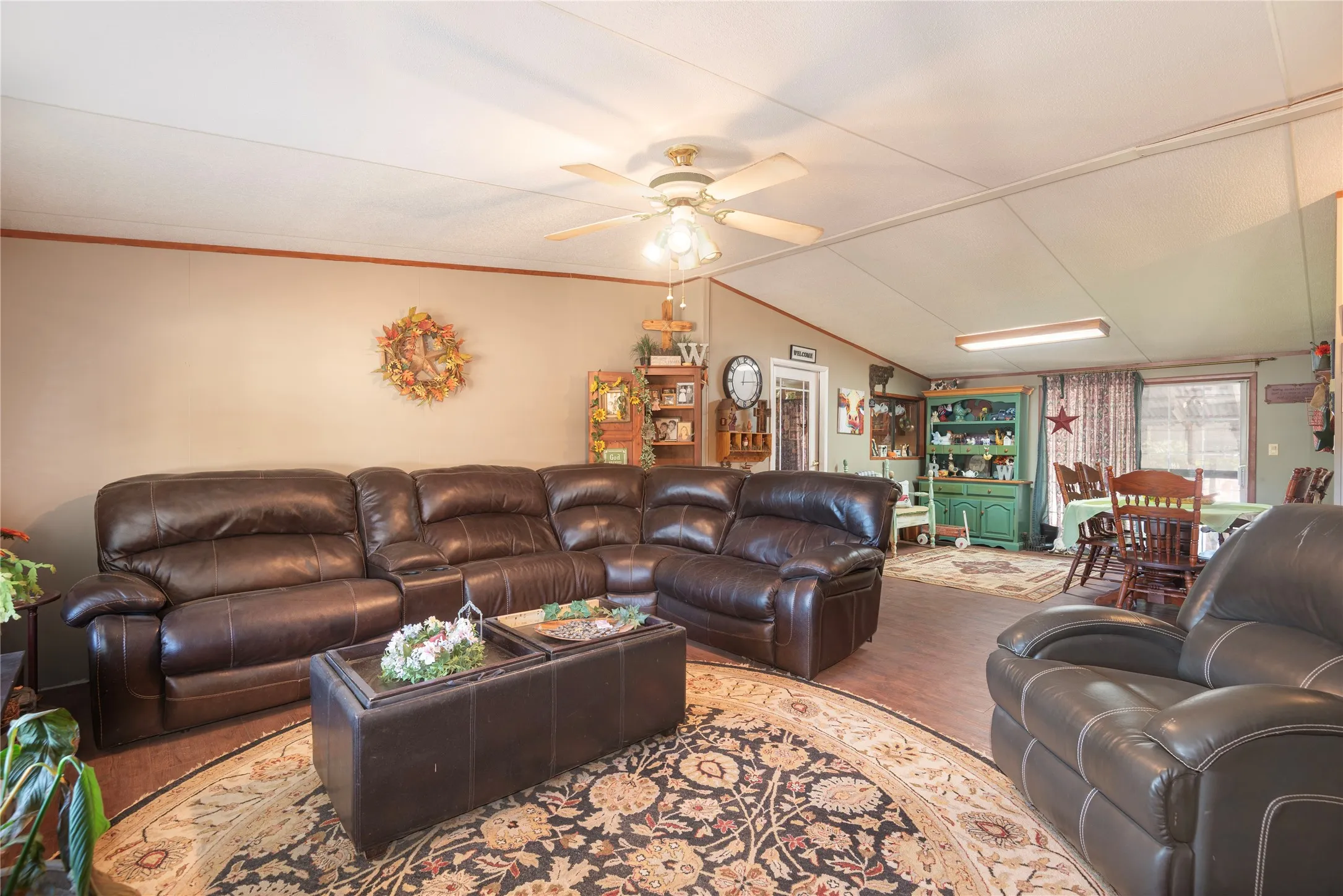 Vaulted ceiling with a ceiling fan, wood-finish flooring, and dining space with built-in cabinetry