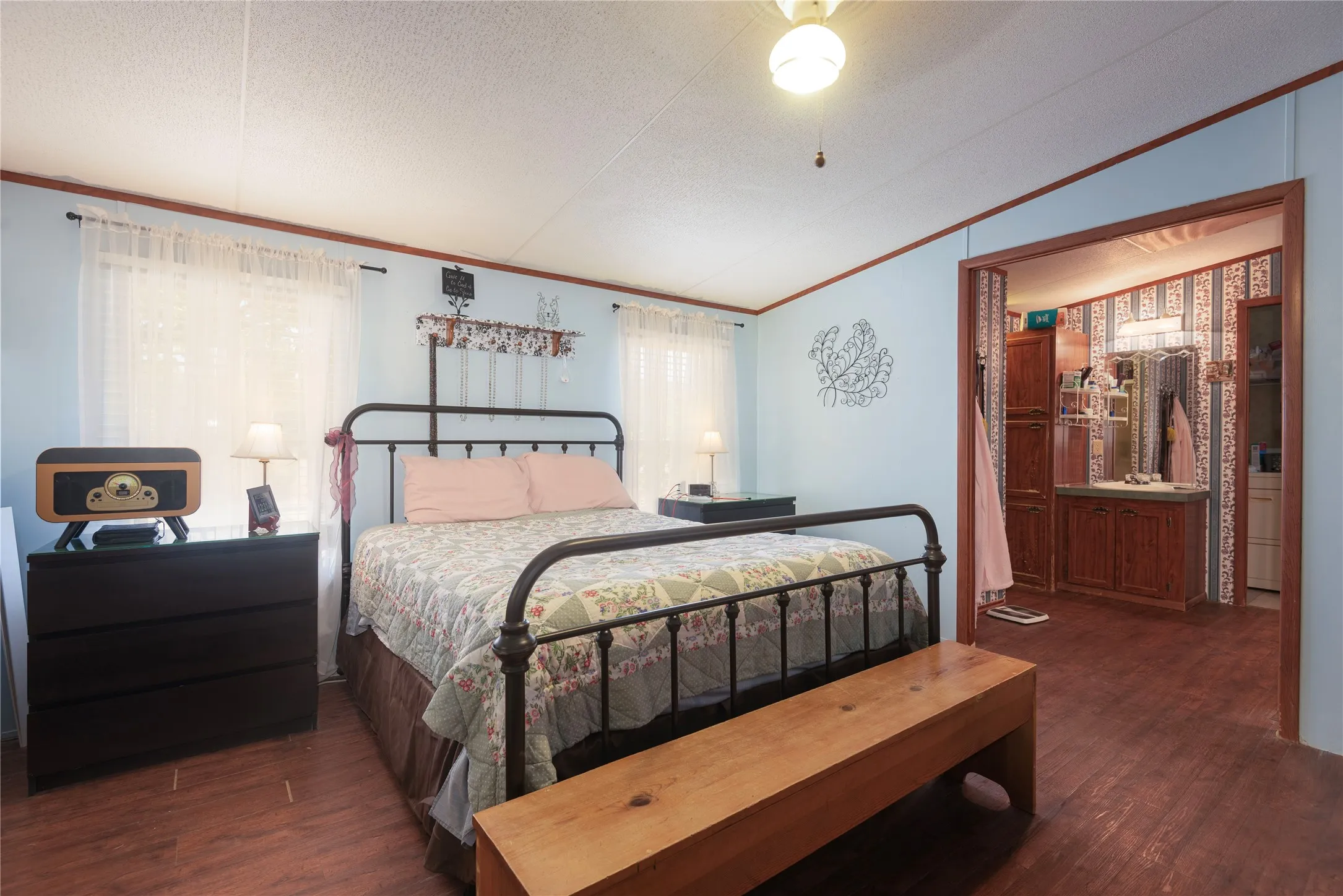 Wood-finish flooring throughout, light blue wall paint, and a ceiling fan with integrated lighting