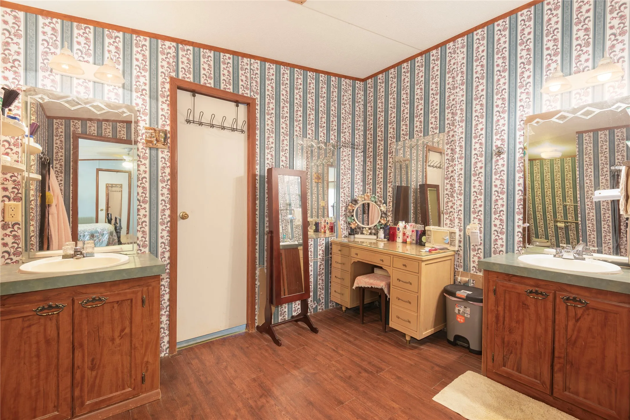 Wood-finish flooring with a dual vanity setup featuring wood cabinetry and integrated sinks