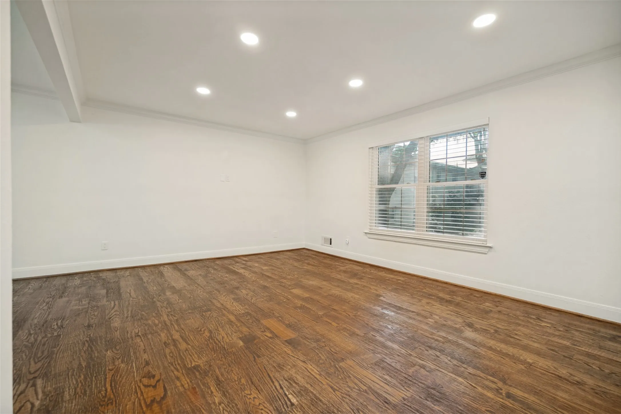 Hardwood flooring, recessed ceiling lighting, crown molding, and a window with blinds