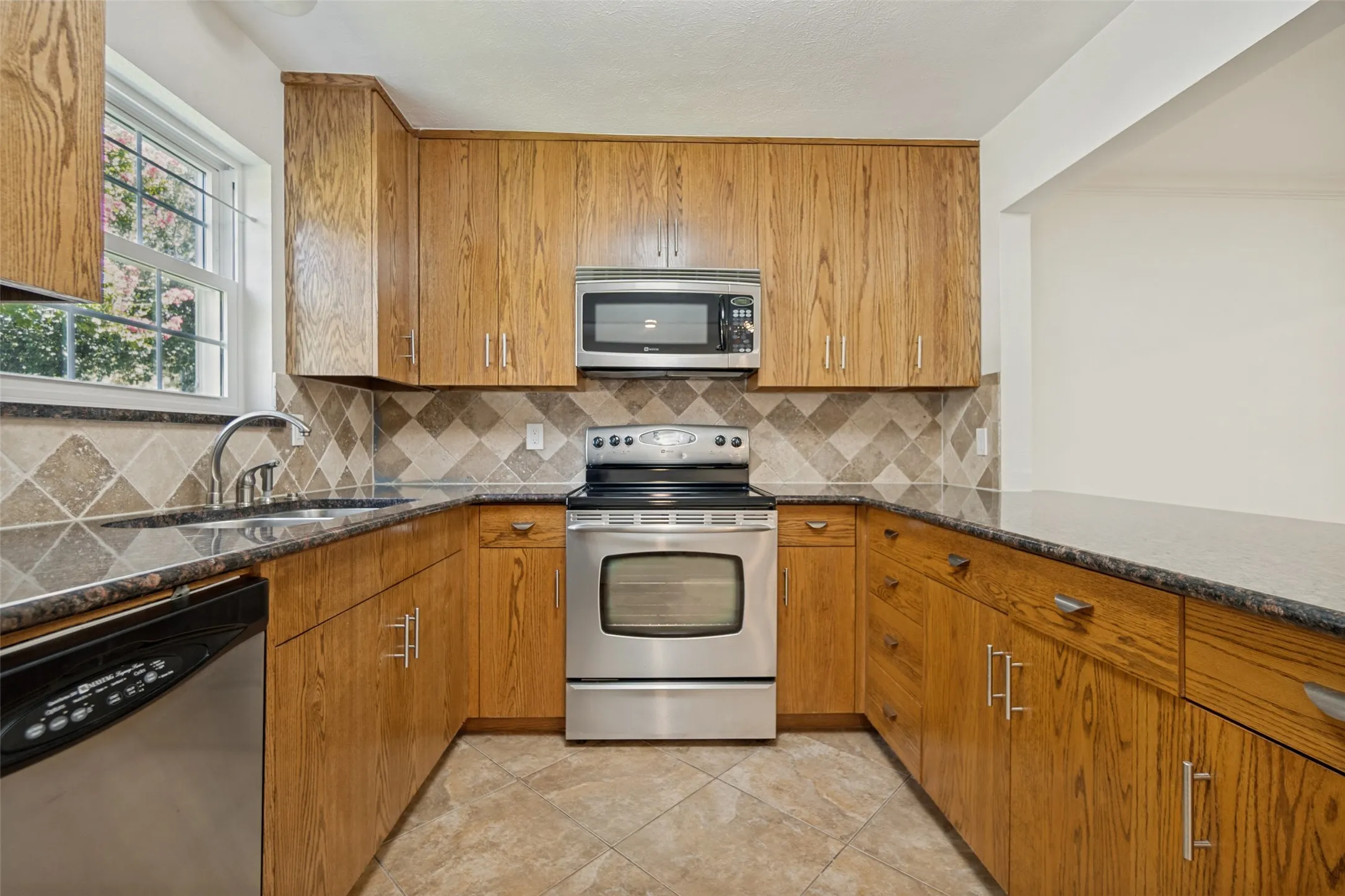 U-shaped kitchen featuring wood-finish cabinetry, stainless steel appliances, and a tiled backsplash