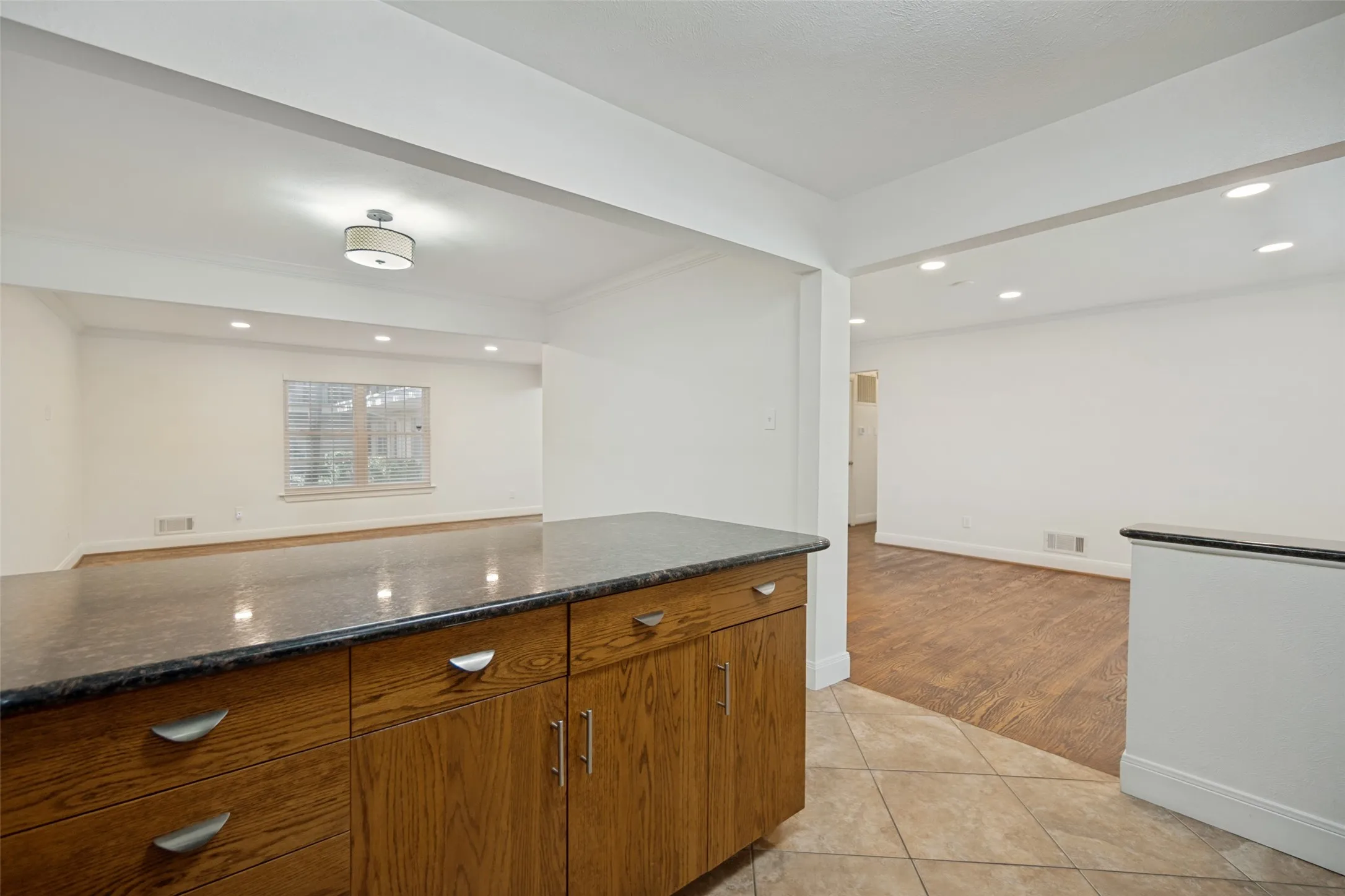 Kitchen island with wood cabinetry, dark countertop, and brushed nickel hardware